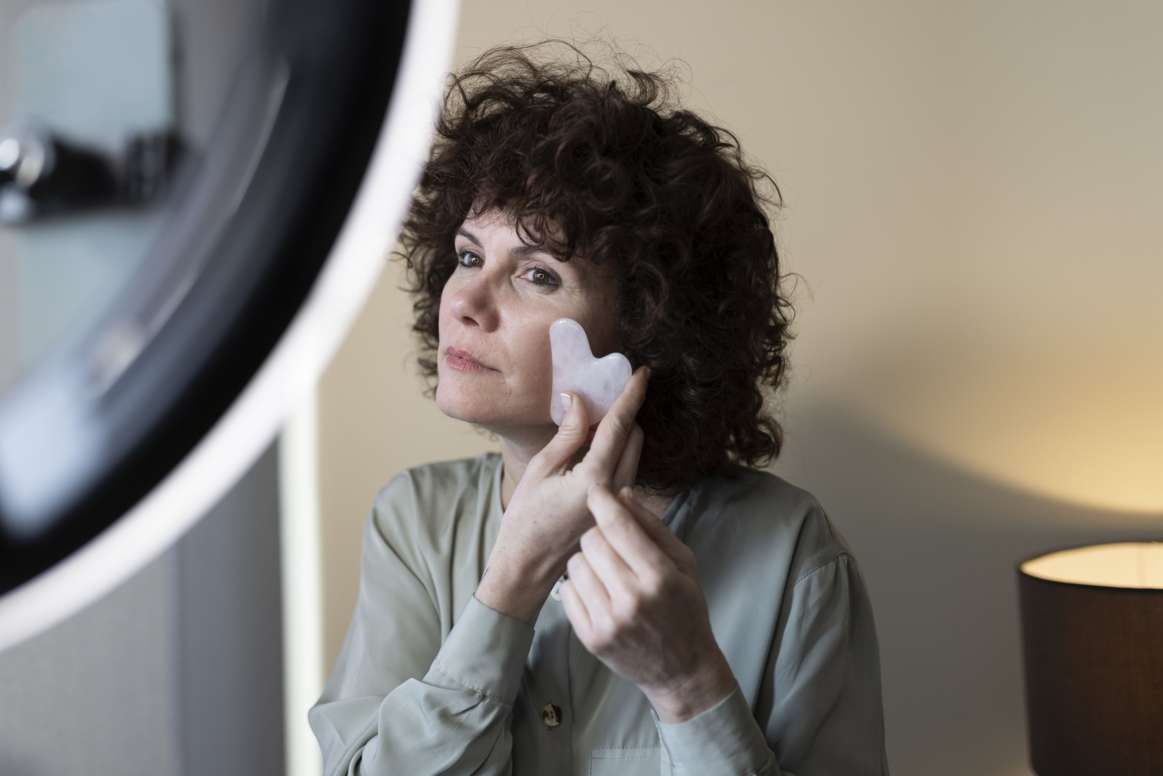 Vlogger massaging with gua sha in front of ring light at home