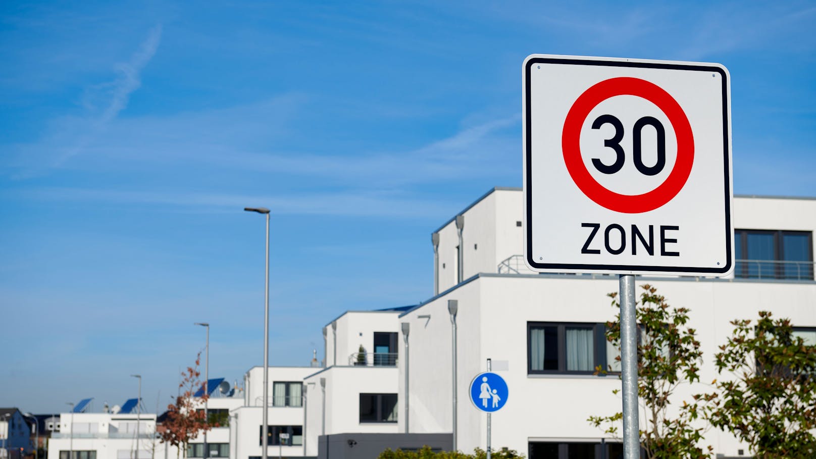 30km/h speed limit road sign in front of modern white family houses in a row. (germany)