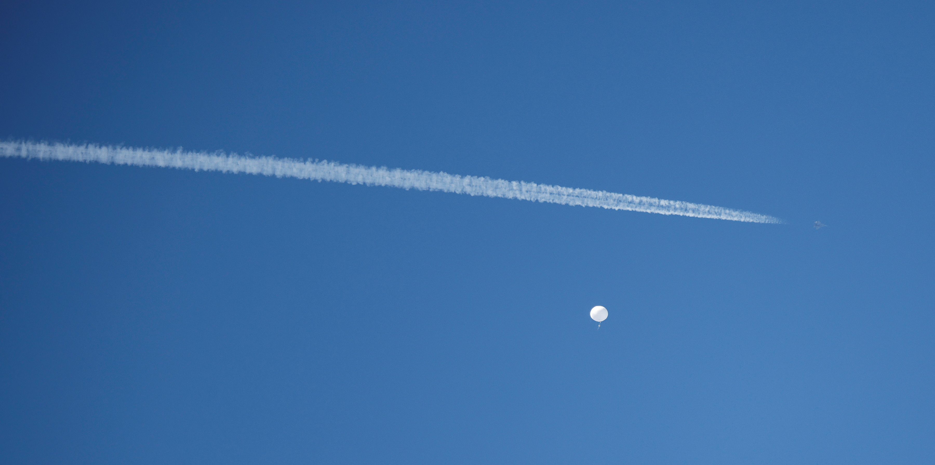A jet flies by a suspected Chinese spy balloon as it floats off the coast in Surfside Beach, South Carolina, U.S. February 4, 2023.  REUTERS/Randall Hill