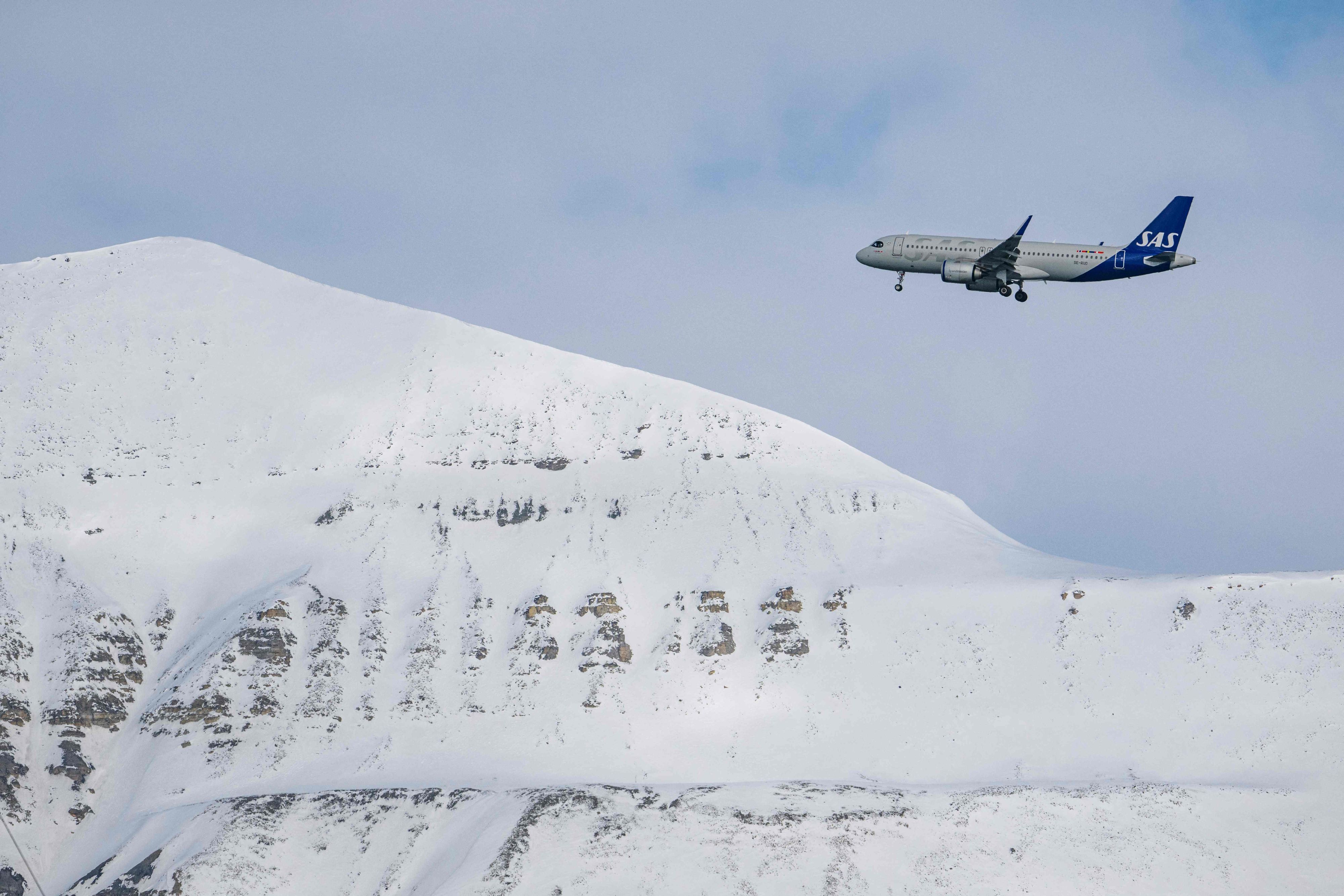 SAS airplane prepares to land at Longyearbyen airport, located on Spitsbergen island, Svalbard Archipelago, northern Norway. - Home to polar bears, the midnight sun and the northern lights, a Norwegian archipelago perched high in the Arctic is trying to find a way to profit from its pristine wilderness without ruining it. The Svalbard archipelago, located 1,300 kilometres (800 miles) from the North Pole and reachable by commercial airline flights, offers visitors vast expanses of untouched nature, with majestic mountains, glaciers and frozen fjords. Or, the fjords used to be frozen. Svalbard is now on the frontline of climate change, with the Arctic warming three times faster than the planet. (Photo by Jonathan NACKSTRAND / AFP) - 20220506_PD18799 - Rechteinfo: Rights Managed (RM) Nur für redaktionelle Nutzung! Werbliche Nutzung erfordert Freigabe: bitte schicken Sie uns eine Anfrage.