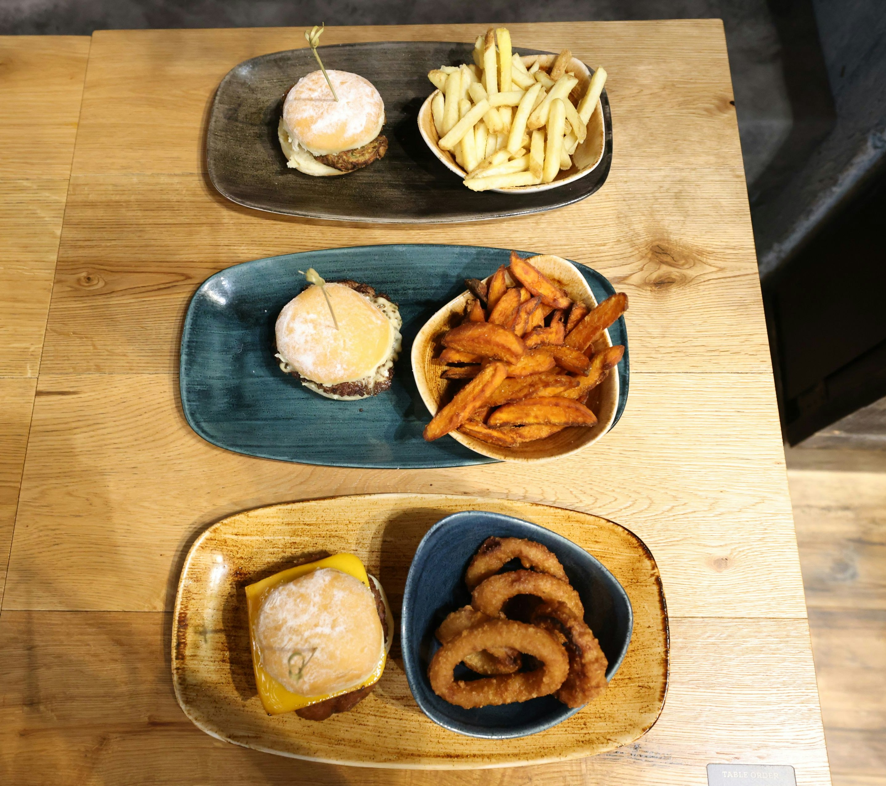 Von oben nach unten: Zucchini-Patty mit Pommes, Rindfleisch-Patty mit Süßkartoffel-Wedges und Falafel-Patty mit vegetarischem Käse und gebackenen Zwiebelringen.