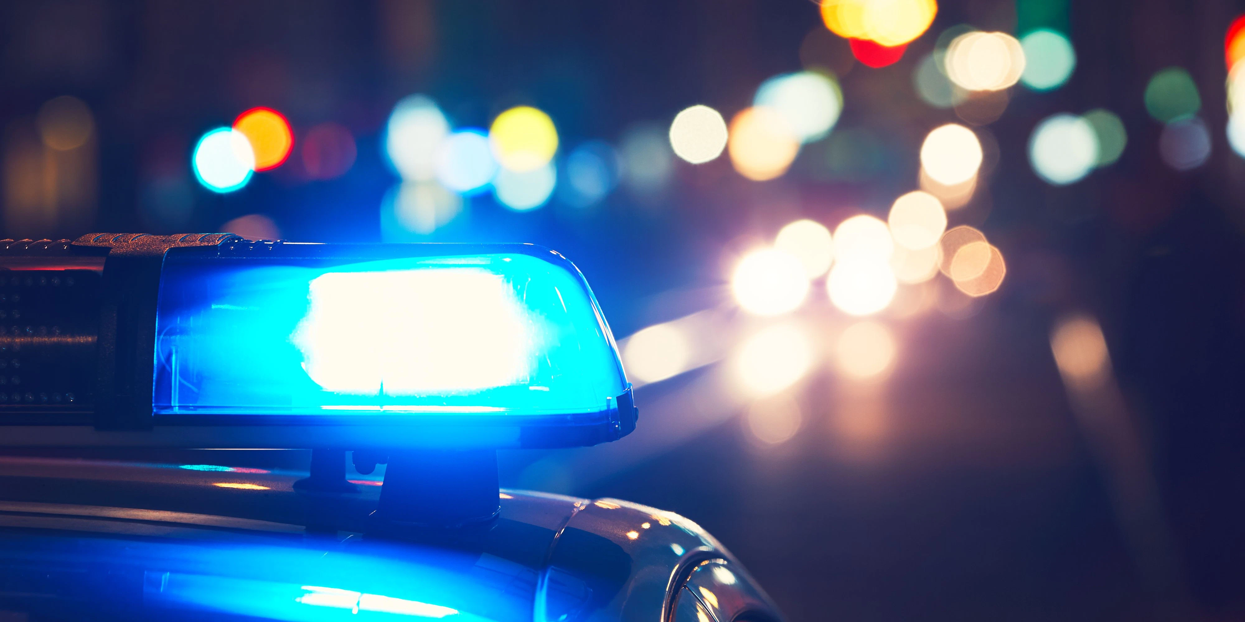Danger on the road. Blue flasher on the police car at night.