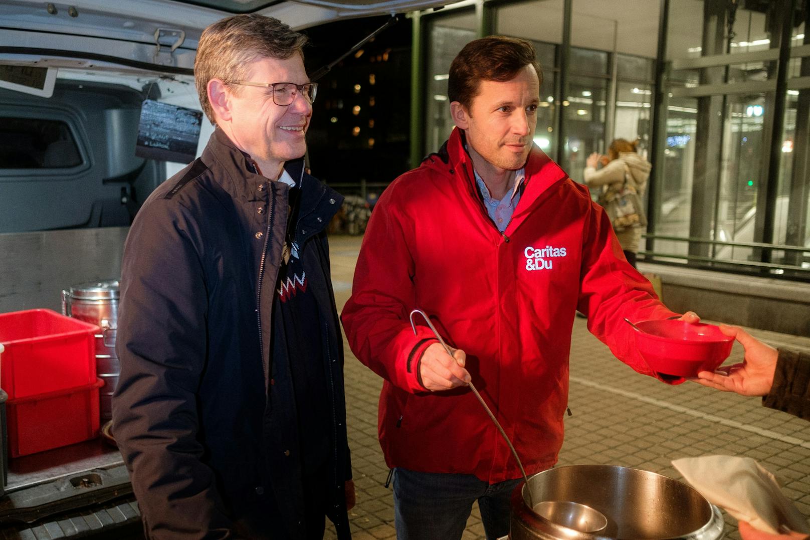 Rudolf Schrefl (Drei) und Klaus Schwertner (Caritas Wien) verteilen gemeinsam warme Suppe und Brot.