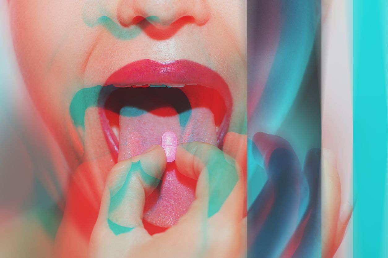 Young woman with colorful psychoactive drug pills on her tongue having psychedelic trip with hallucinations