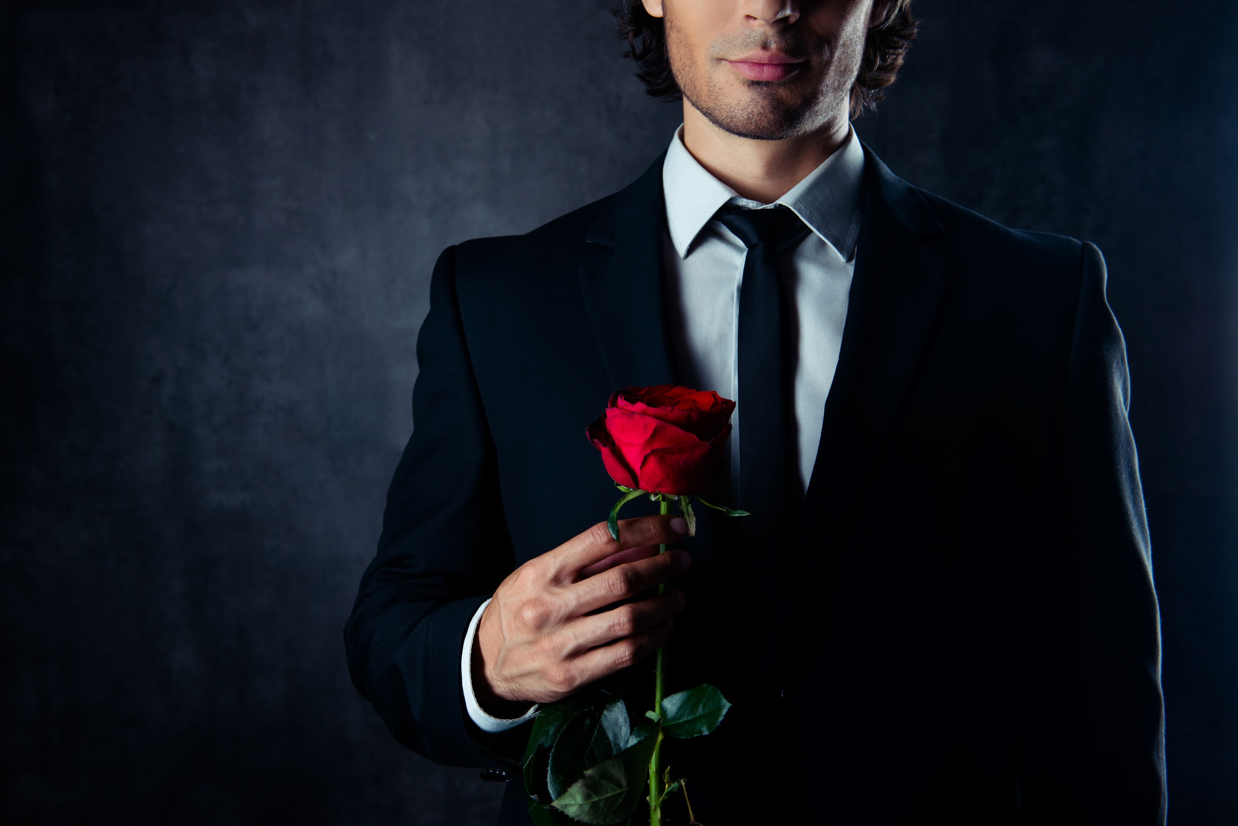 Close up of handsome young boyfriend holding red rose