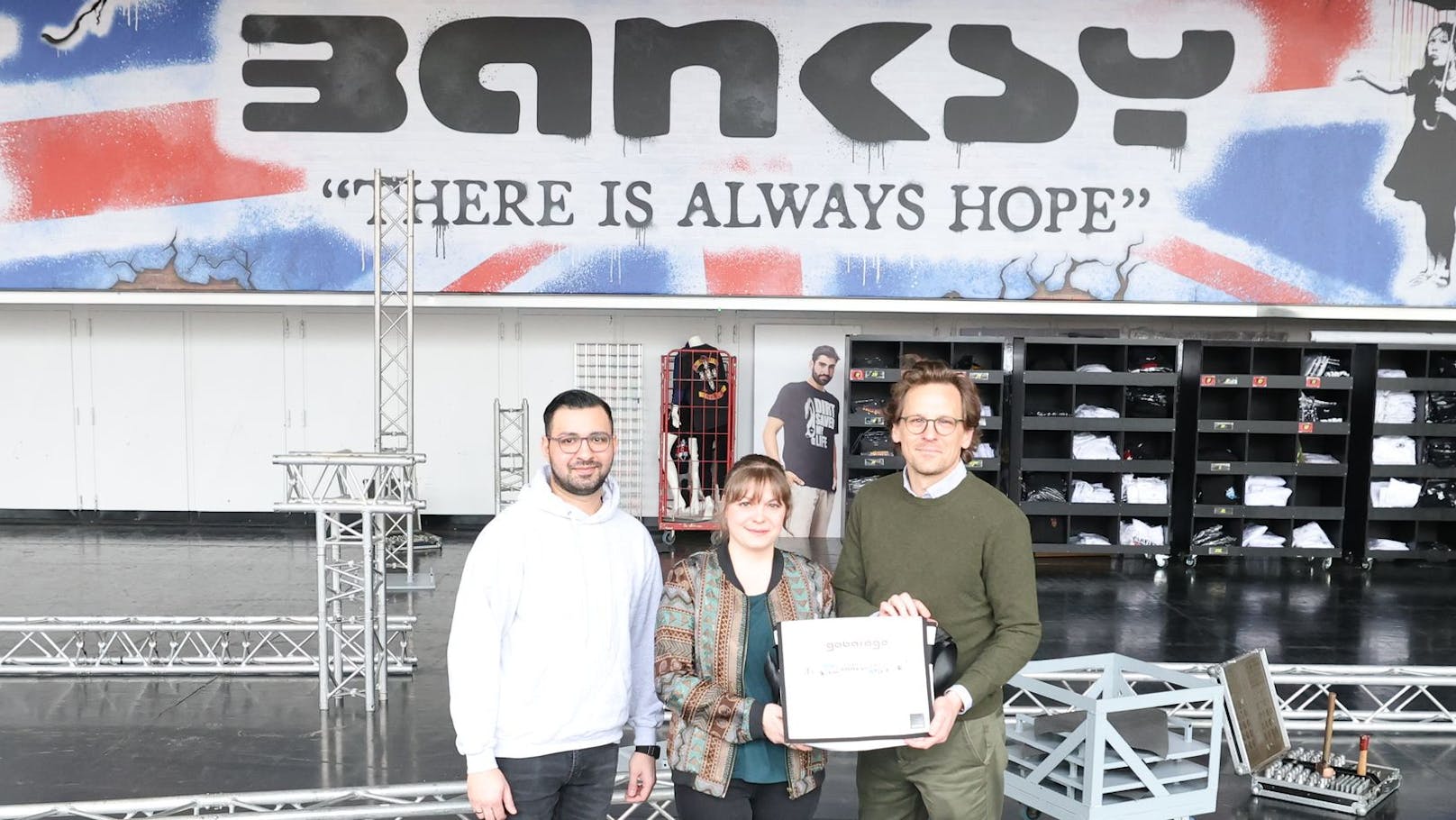 Ausstellungsleiter der&nbsp;COFO Mikica Dimitrijevic, Birgit Rauer-Seifert von Gabarage und Matthäus Zelenka als Geschäftsführer der Wiener Stadthalle (v.l.) vor einem Banksy-Banner von dreißig mal drei Metern.
