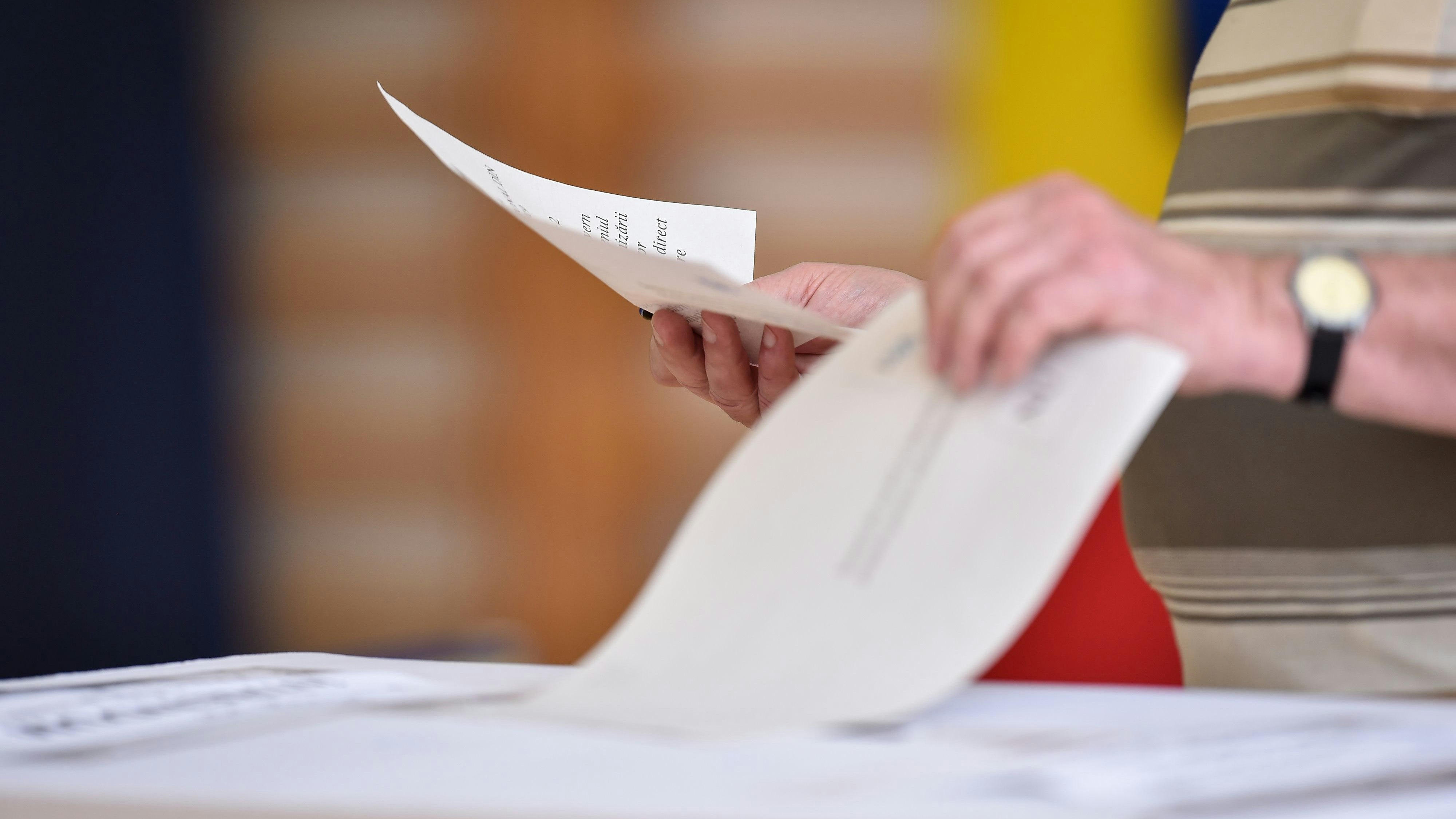 Hand of a person casting a vote into the ballot box during elections