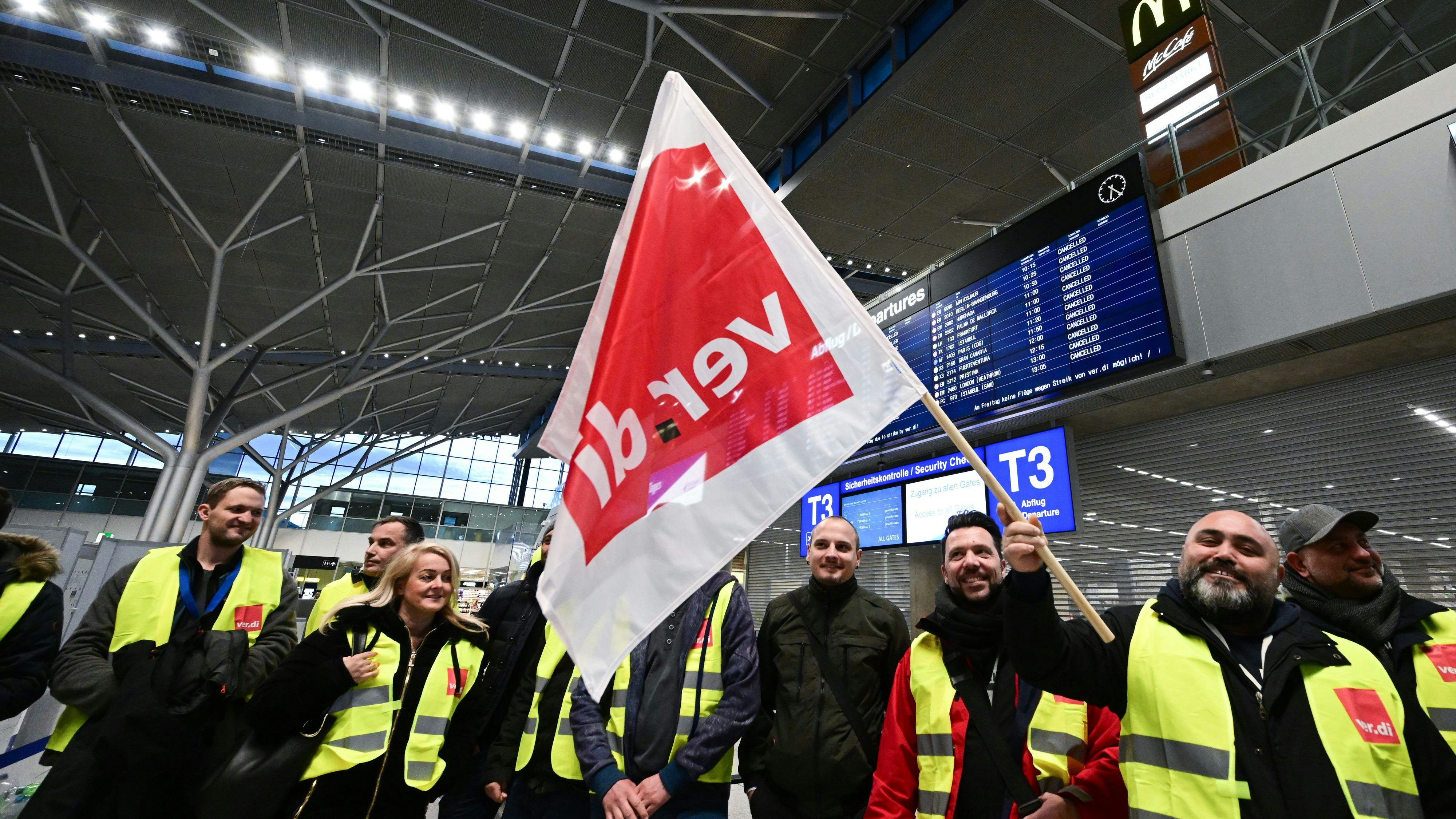 Download von www.picturedesk.com am 17.03.2023 (07:25).  17 March 2023, Baden-Württemberg, Stuttgart: Striking employees of Stuttgart Airport stand with vests of the trade union Verdi in the empty departure hall at Stuttgart Airport. Flights have been canceled due to a Verdi strike. Photo: Bernd Weißbrod/dpa - 20230317_PD0988 - Rechteinfo: Rights Managed (RM)
