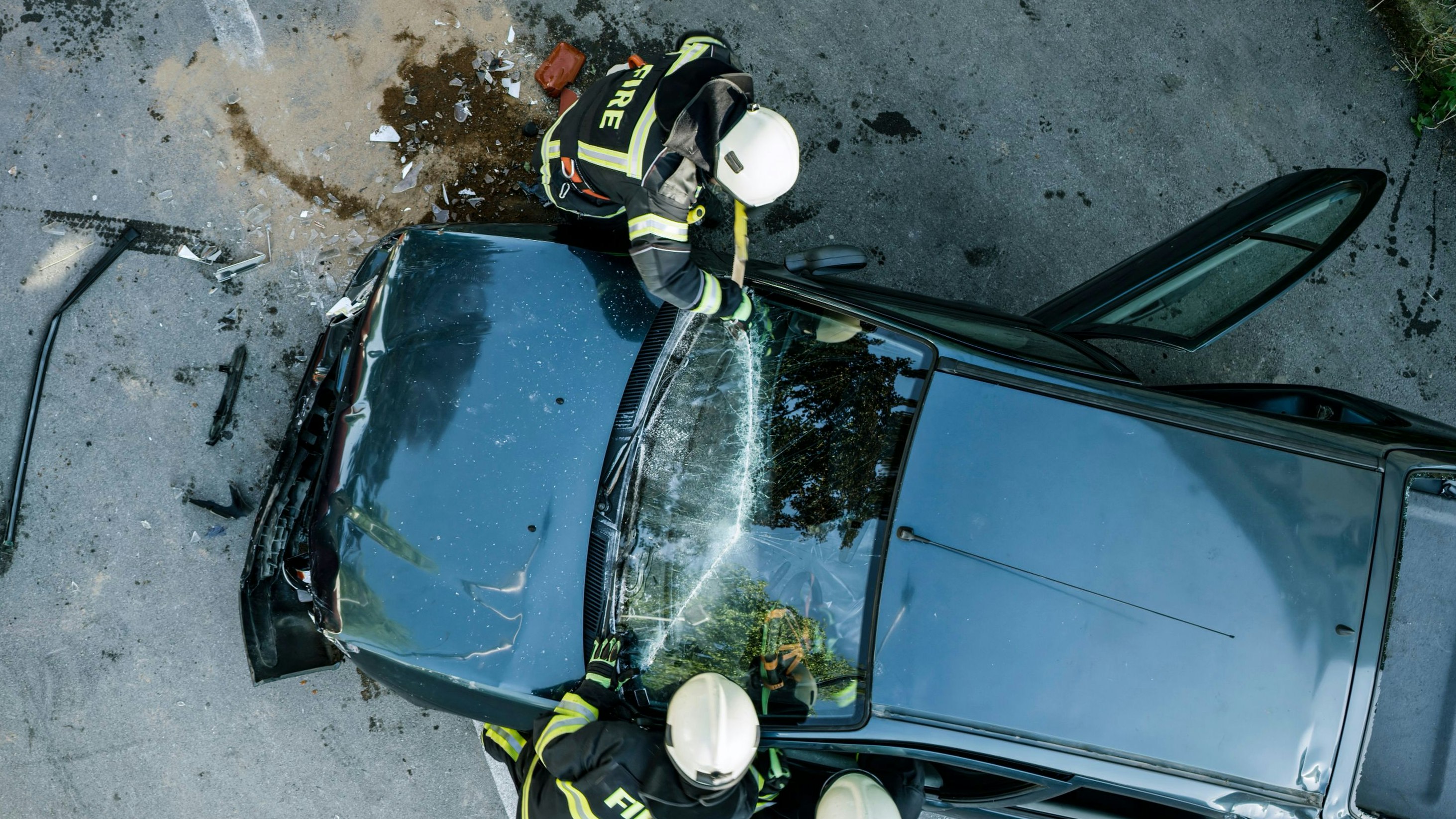 Firefighters using a glass cutter to cut car windscreen after accident.