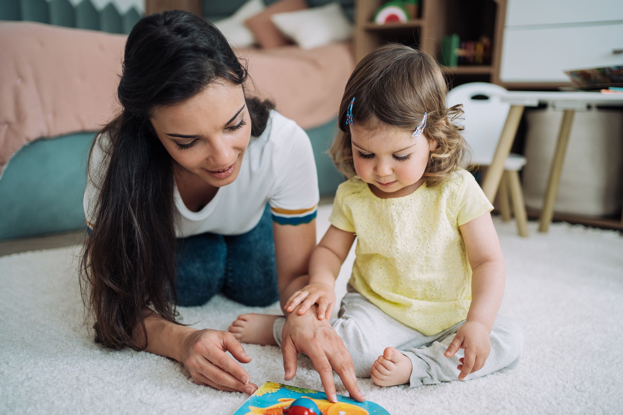 Shot of happy mother playing with her small toddler girl on the floor at home.