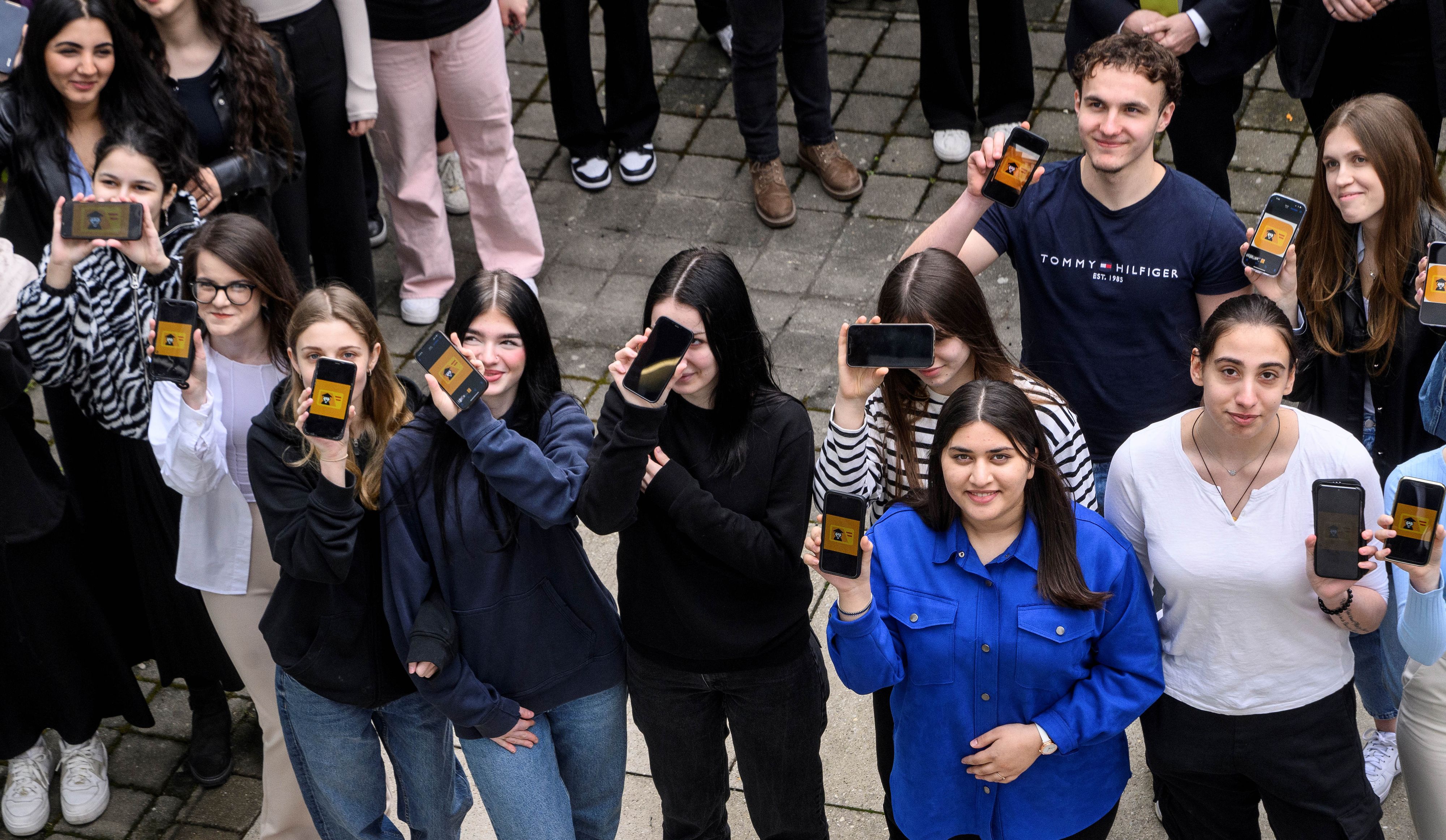 Schüler und Schülerinnen zeigen ihre Smartphones mit der installierten App bei der Präsentation des digitalen Schülerausweises edu.digicard