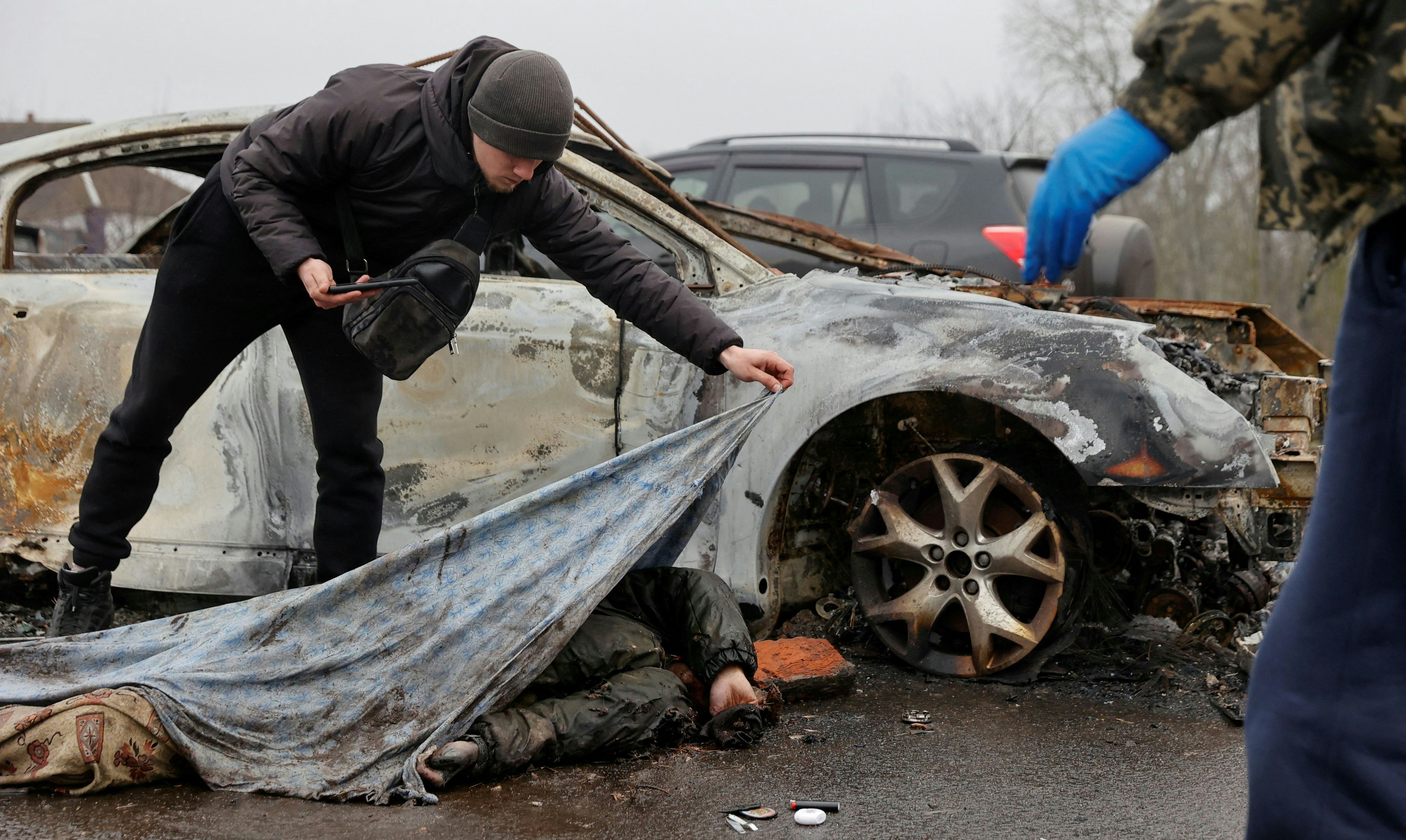 Ein Mitarbeiter eines Bestattungsunternehmens mit einem toten Zivilisten in der Stadt Nova Basan im April 2022.
