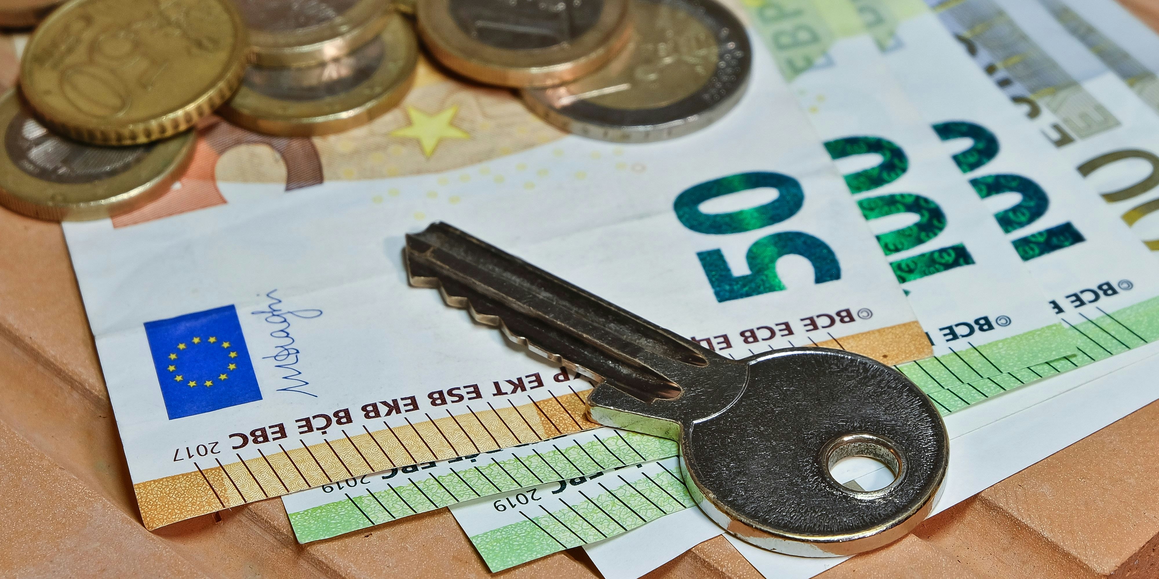 A key on euro coins and banknotes on a brick.