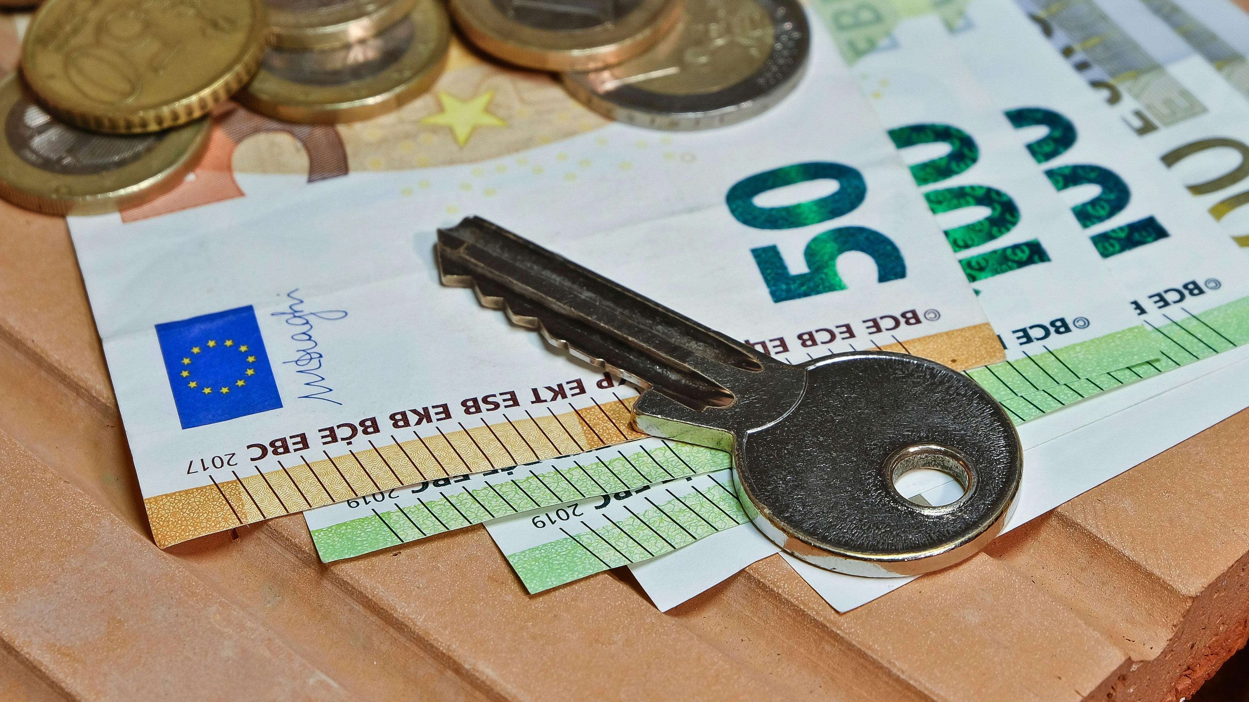 A key on euro coins and banknotes on a brick.