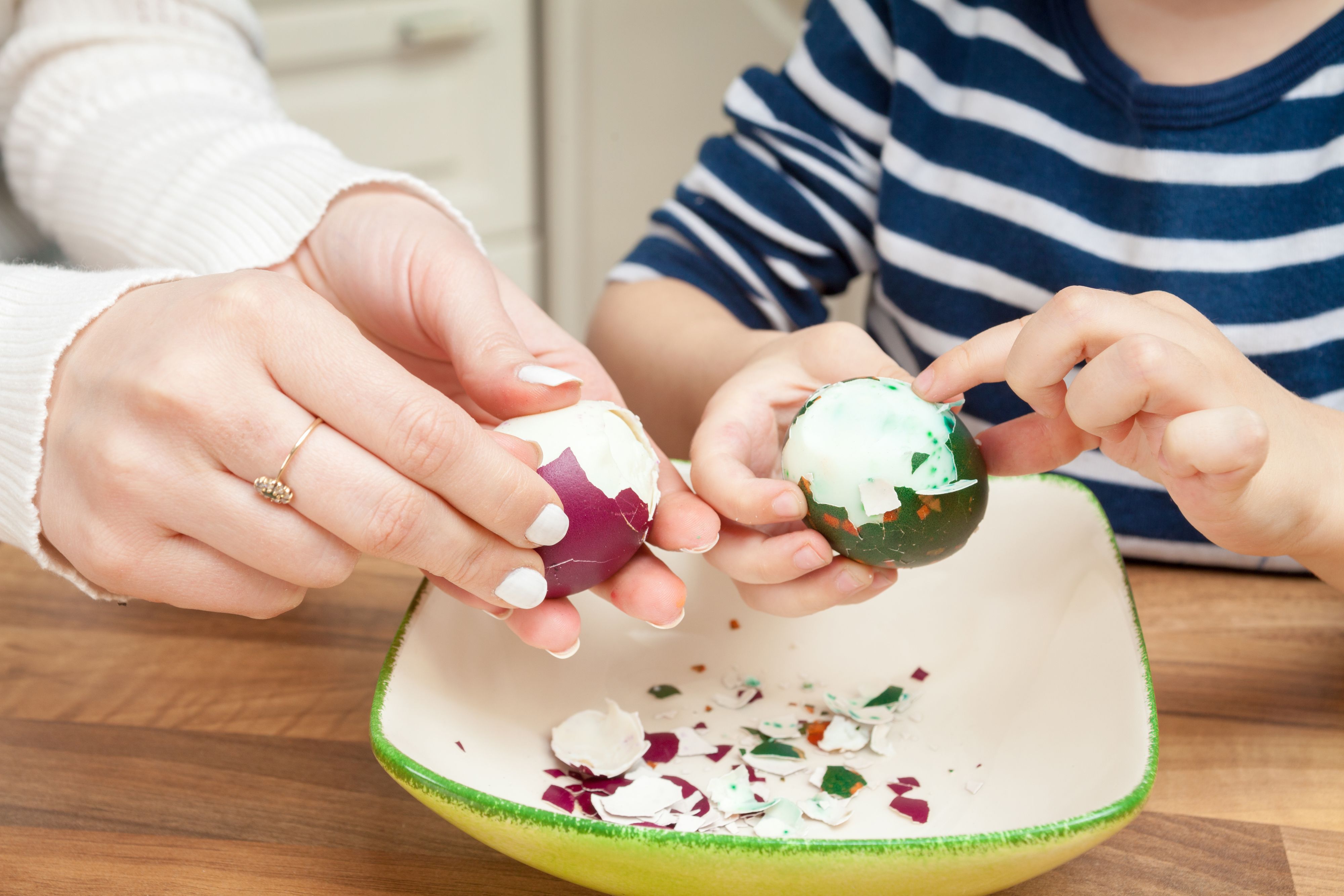 Close up of mother and son peeling Easter eggs.