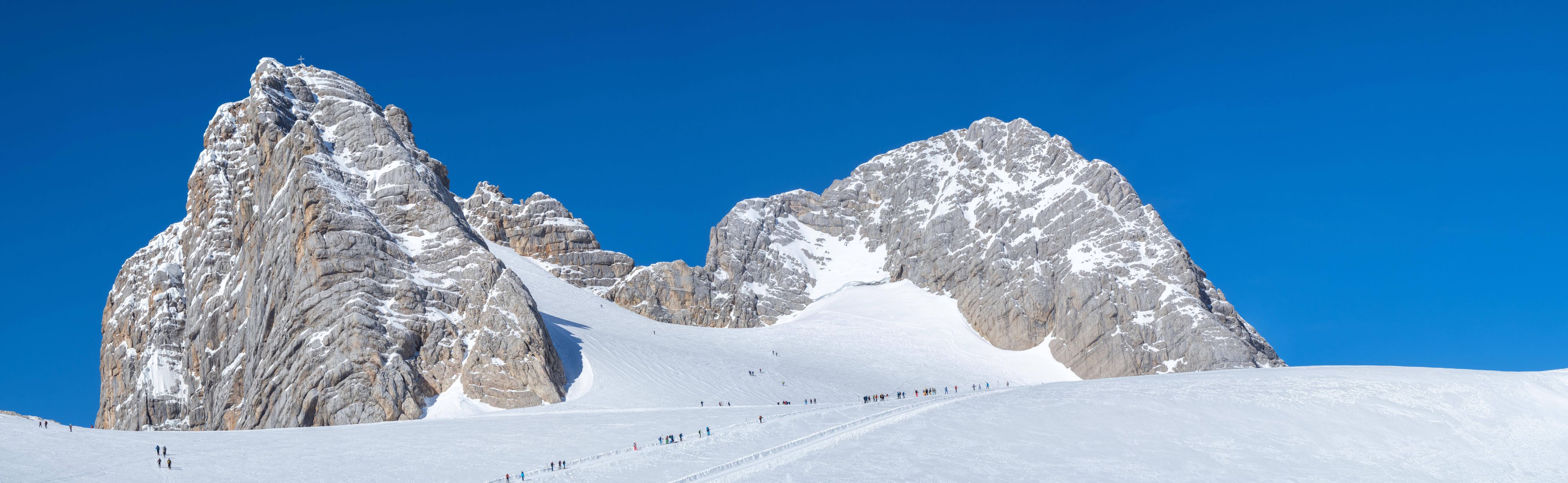 Skitourengeher auf dem Weg zum Hohen Dachstein mit Gipfelkreuz. Der Dachstein ist der höchste Berg der Steiermark.