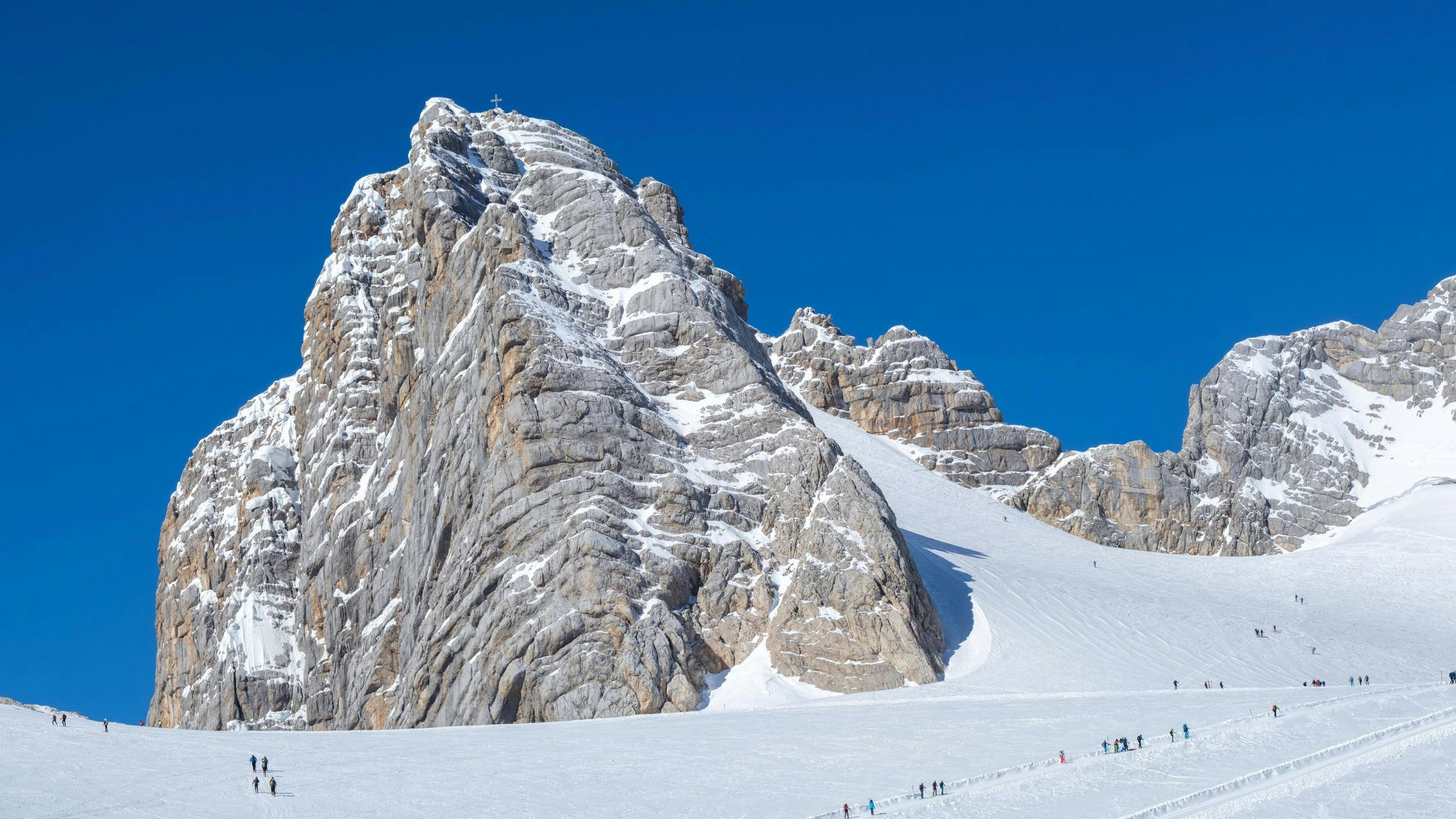 Skitourengeher auf dem Weg zum Hohen Dachstein mit Gipfelkreuz (l.). Der Dachstein ist der höchste Berg der Steiermark. 