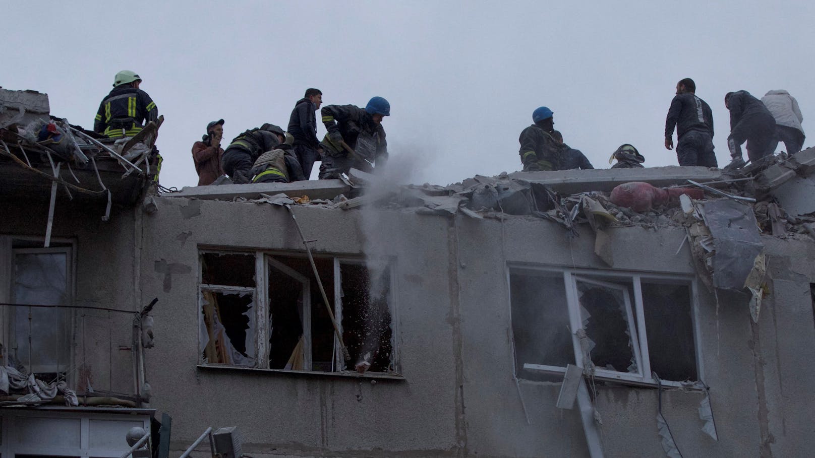 Rettungskräfte und Freiwillige arbeiten vor Ort an dem Wohnhaus, das durch einen russischen Militärschlag beschädigt wurde.