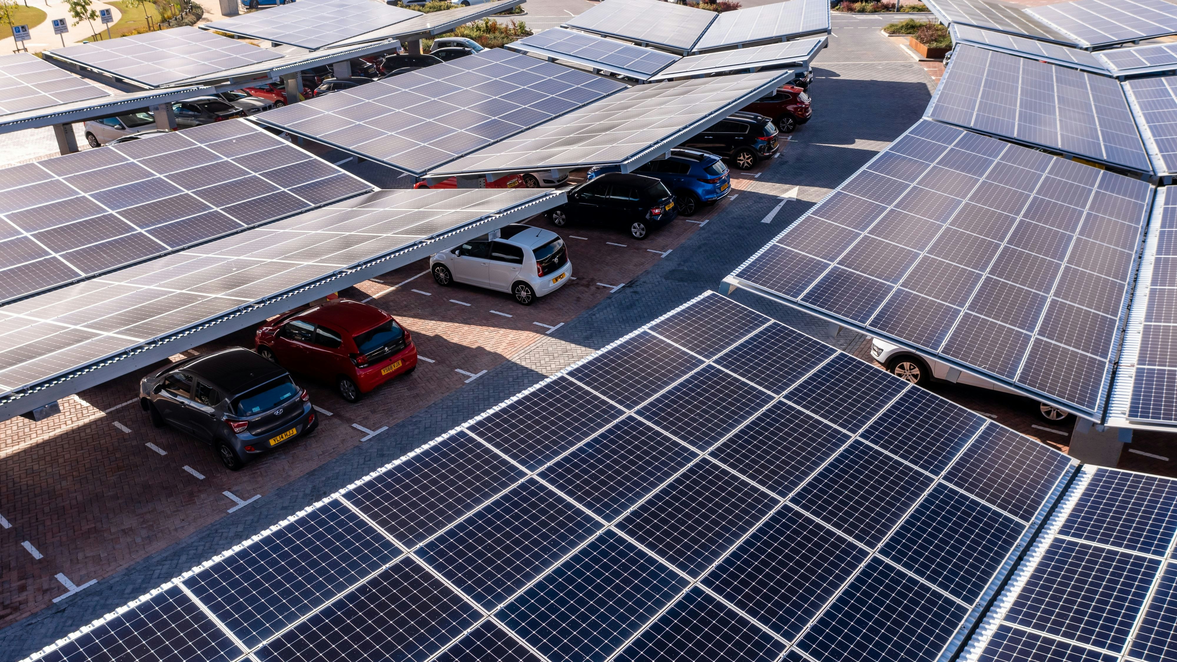 Leeds, UK - August 19, 2022. Aerial view above innovative solar panels located on a car parking lot rooftops making good use of small space in a city and providing sustainable energy for electric vehicle charging