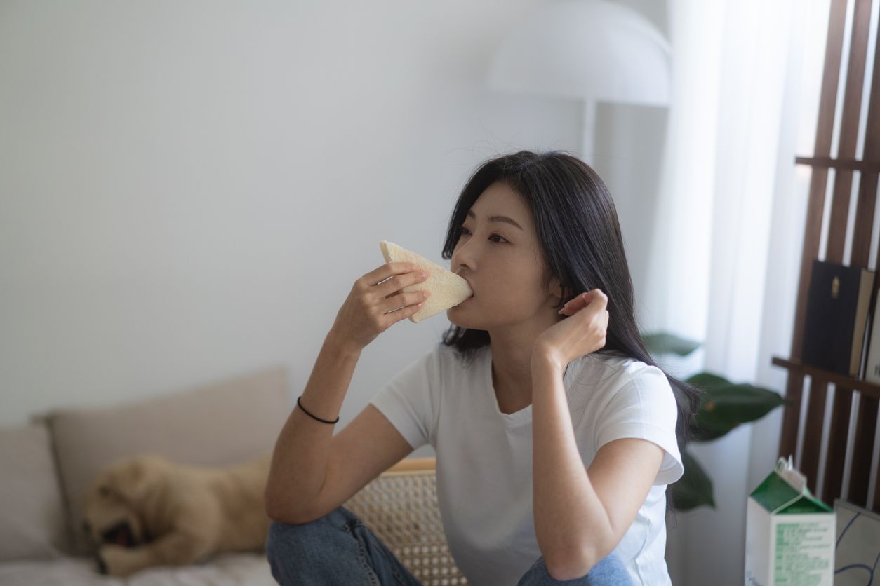 A young South Korean female eating a tasty sandwich at home