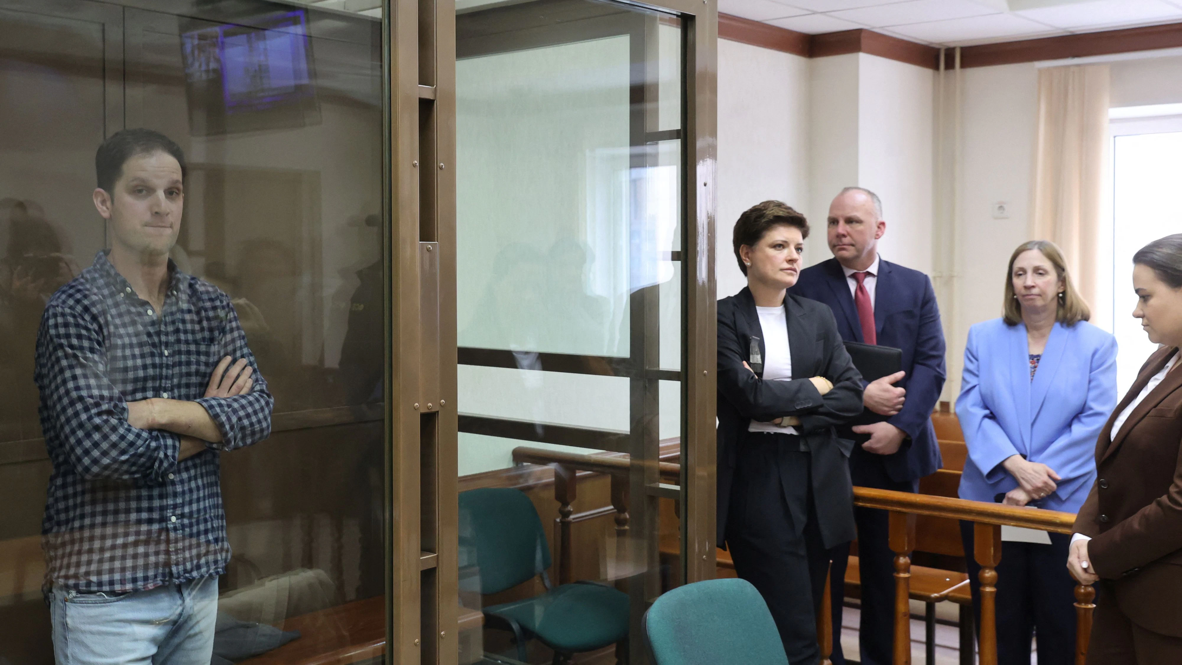 Wall Street Journal reporter Evan Gershkovich, who was detained in March while on a reporting trip and charged with espionage, stands behind a glass wall of an enclosure for defendants, while U.S. Ambassador to Russia Lynne Tracy and lawyers Tatyana Nozhkina and Maria Korchagina appear in a courtroom before a hearing to consider an appeal against Gershkovich's detention, in Moscow, Russia April 18, 2023. REUTERS/Yulia Morozova