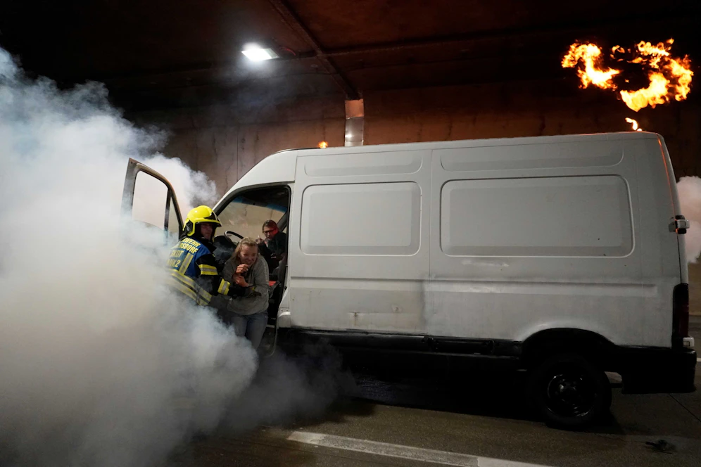Einsatzkräfte halfen einer Frau aus einem brennenden Auto.