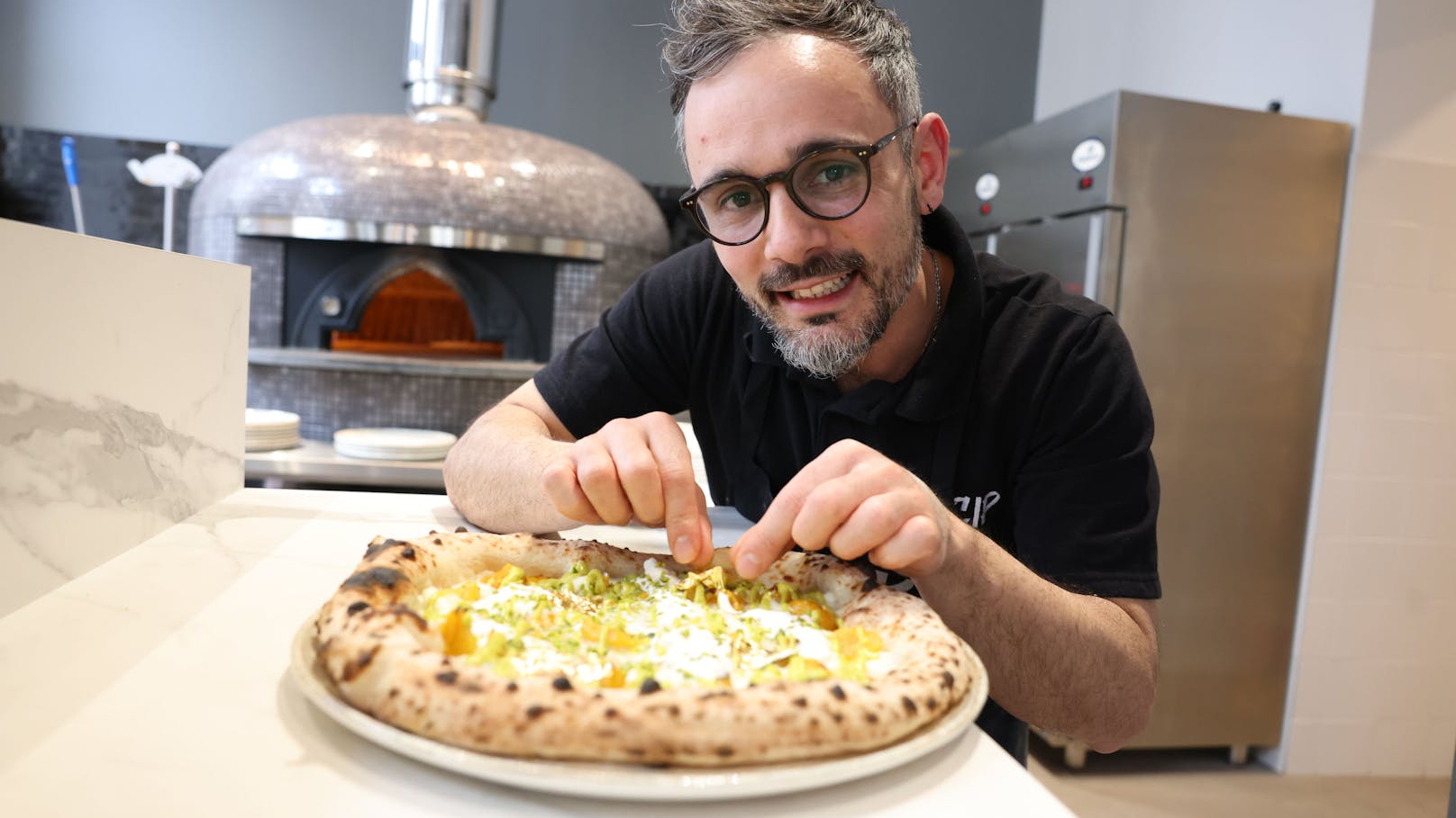 Pizzabäcker Fabio Saccoccio mit seiner Sunset Pizza mit Blattgold auf 72 Stunden lang fermentiertem Teig.