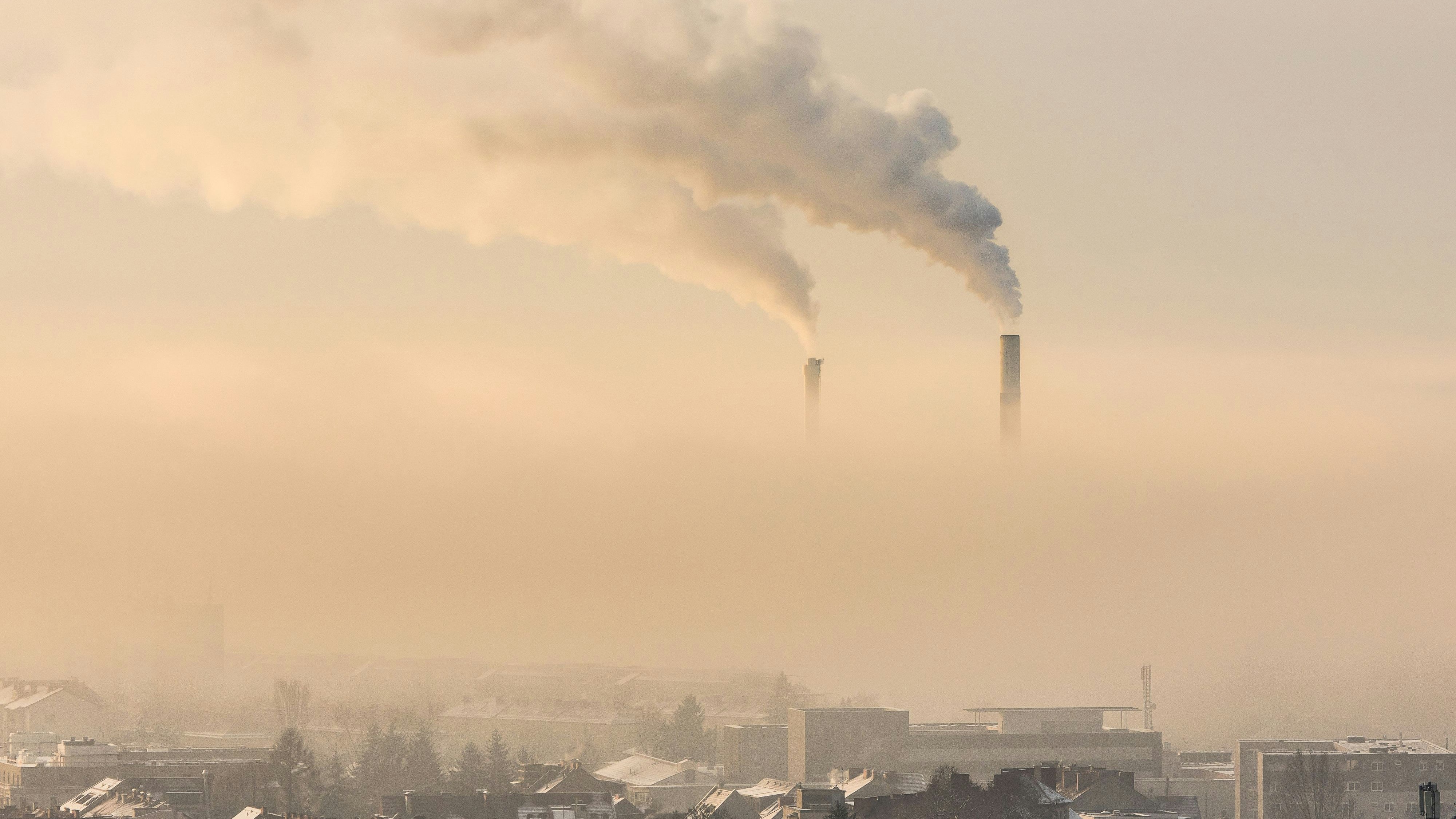 Smoking industrial chimneys emitting fine dust and carbon dioxide over Graz in Austria on a foggy winter morning