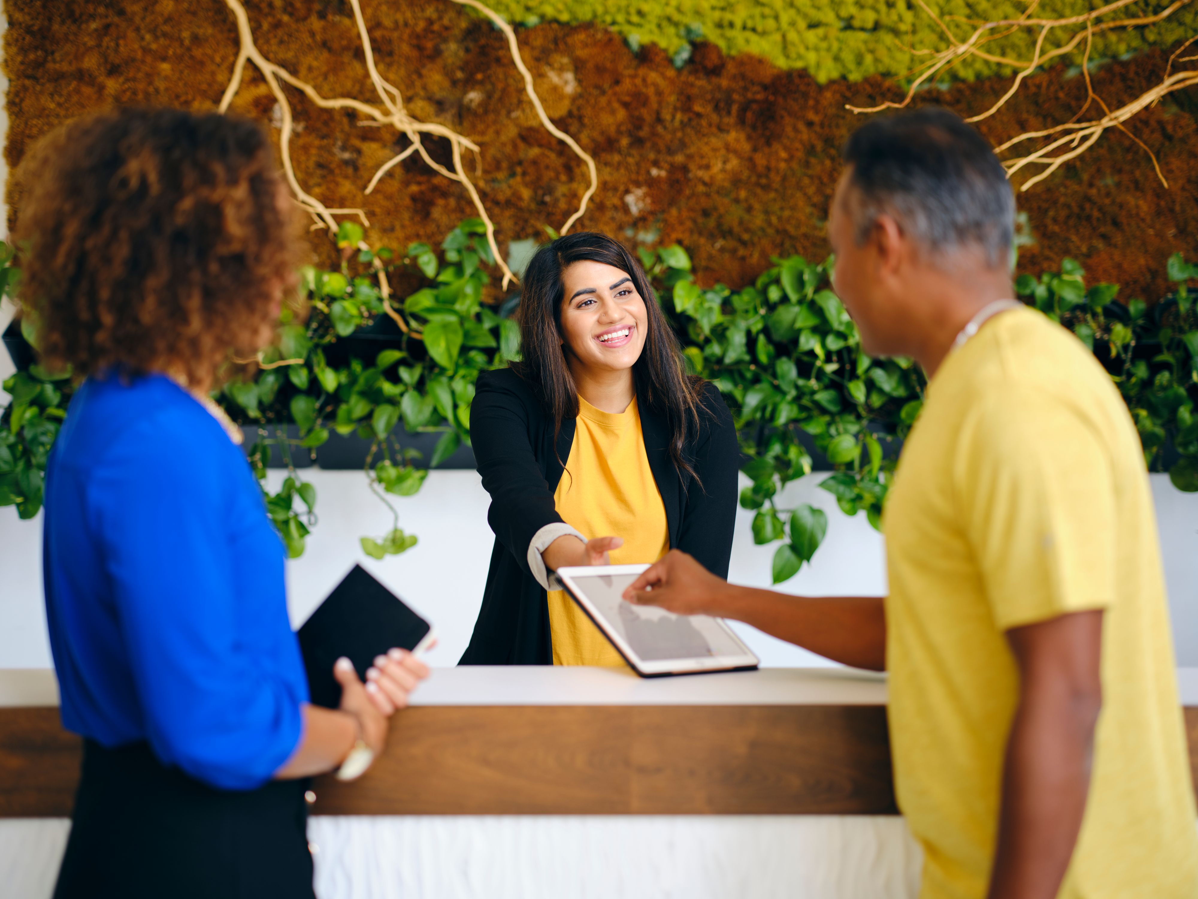 A receptionist behind a desk in a business or hotel lobby.