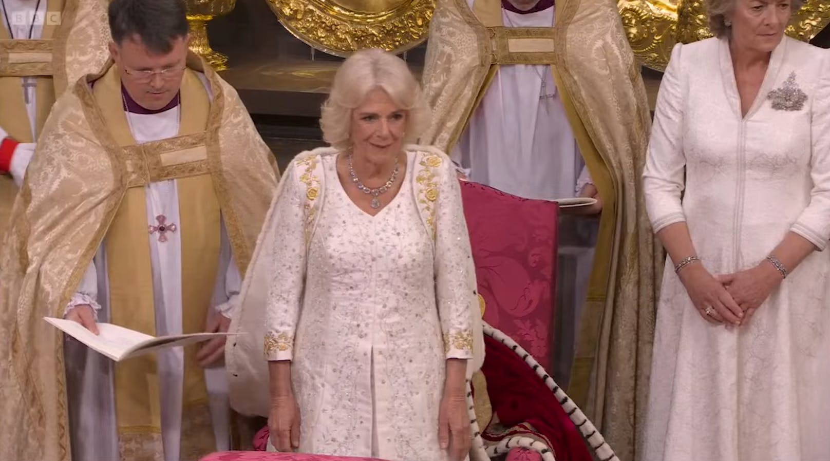 Queen Camilla strahlt in einem weißen Krönungskleid. 