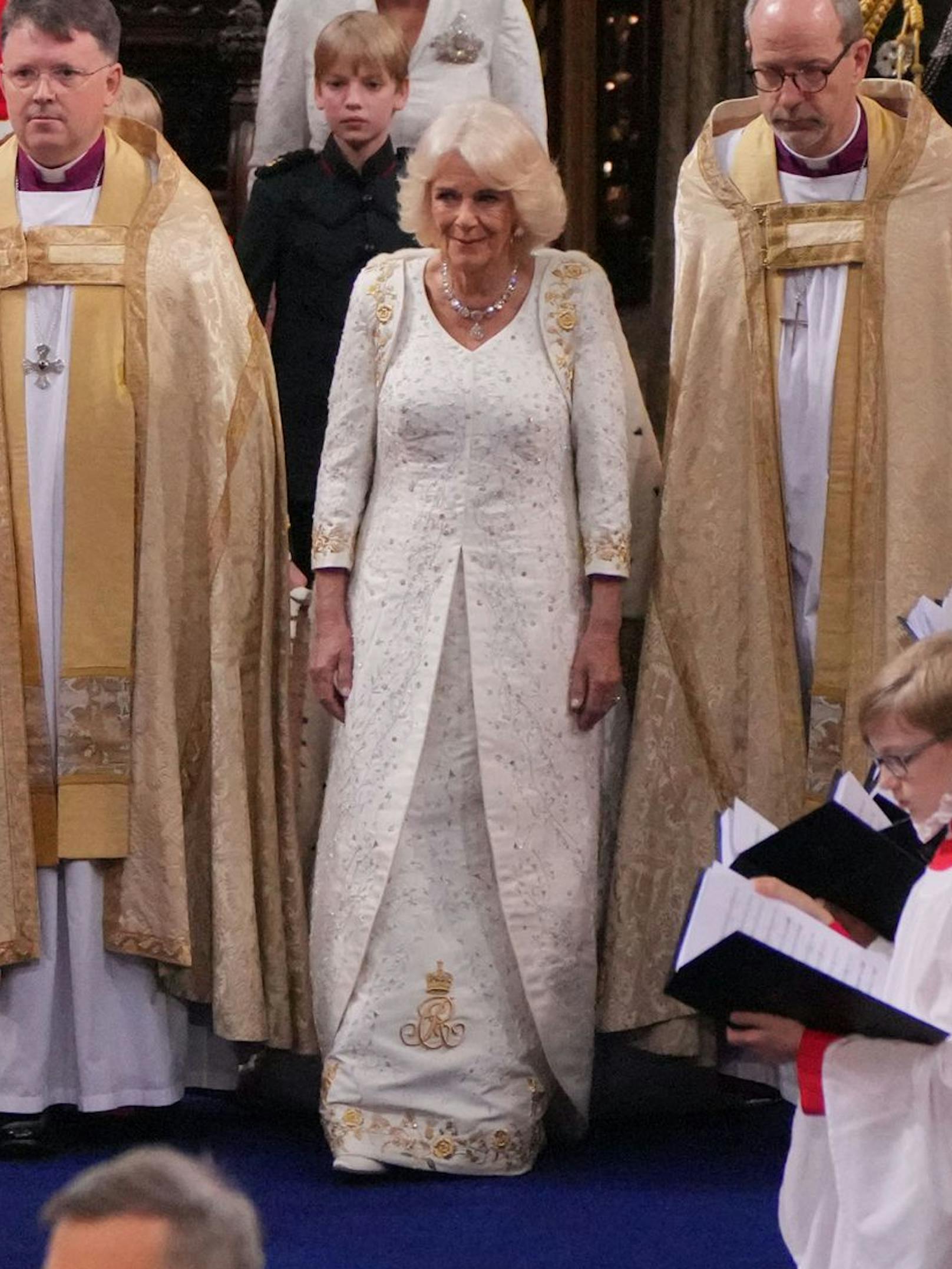 Queen Camilla trug eine maßgeschneiderte Bruce-Oldfield-Robe mit geschwungenen Formlinien, die in eine kurze Schleppe übergingen.&nbsp;