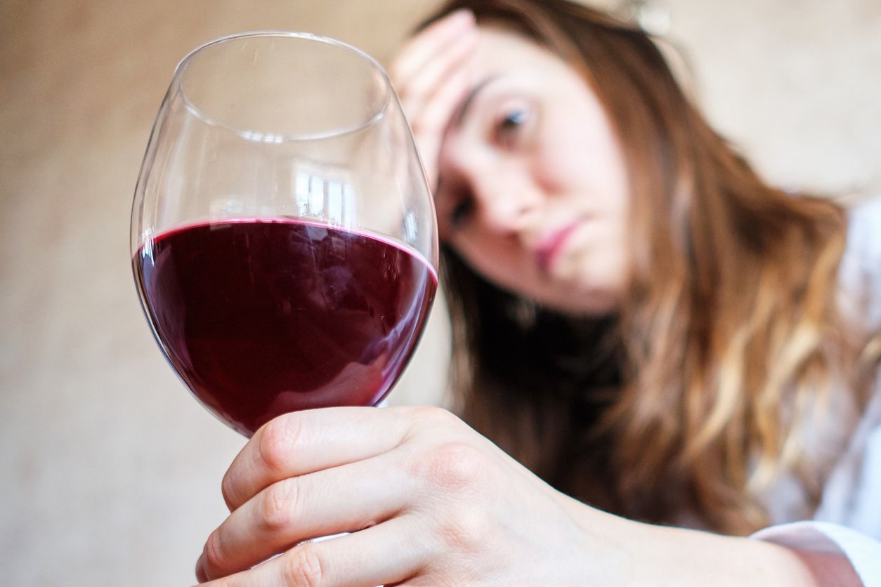 A woman is sitting on a sofa with a glass of wine.
