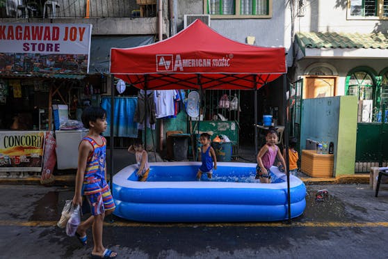 Kinder kühlen sich in einem Pool in Manila ab. Auf den Philippinen warnen die Behörden vor Gesundheitsschäden durch die Hitze.