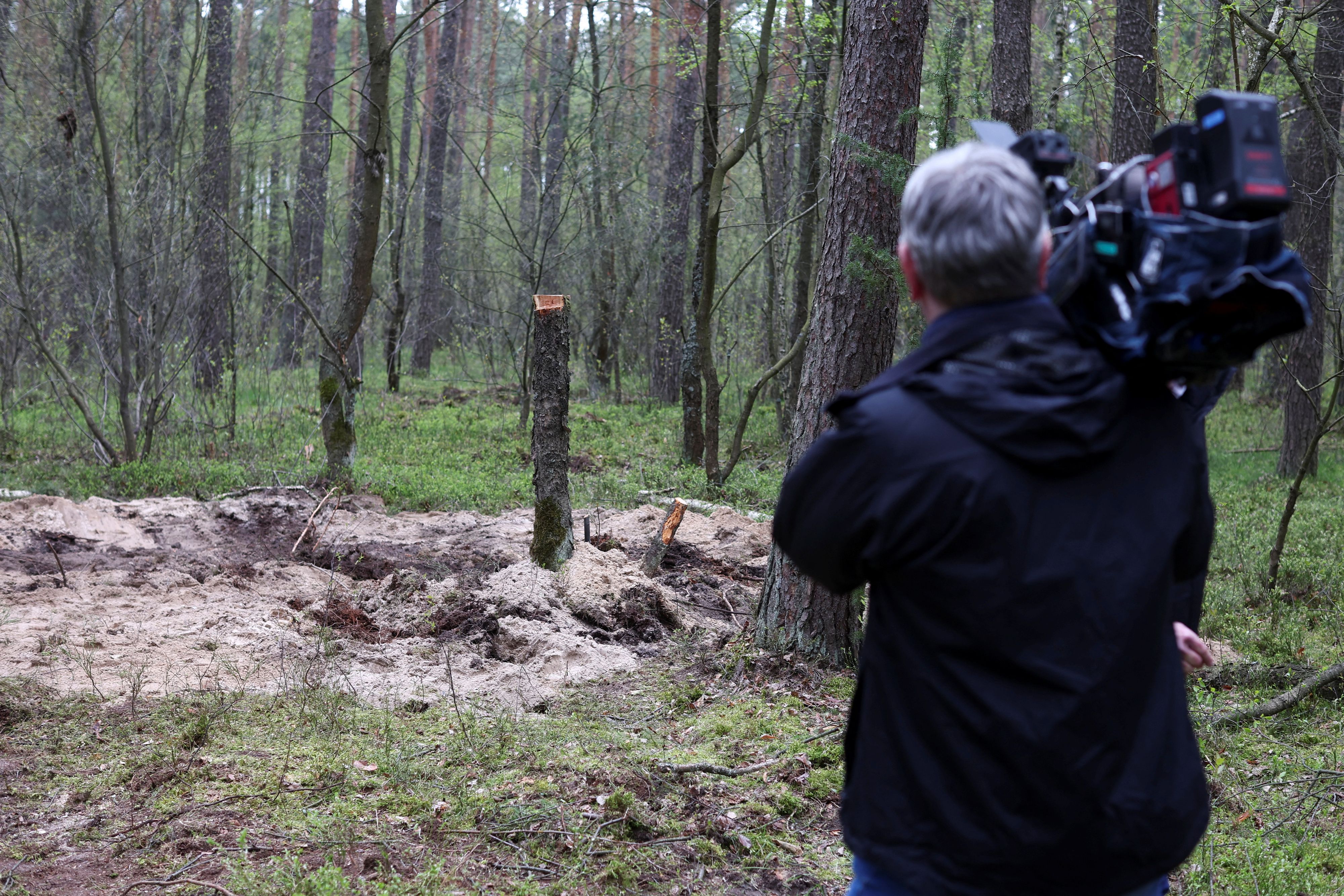 A member of the media holds a camera at the site where the remains of an unidentified military object were found in a northern Polish forest, near the city of Bydgoszcz, Poland, April 27, 2023. REUTERS/Kacper Pempel