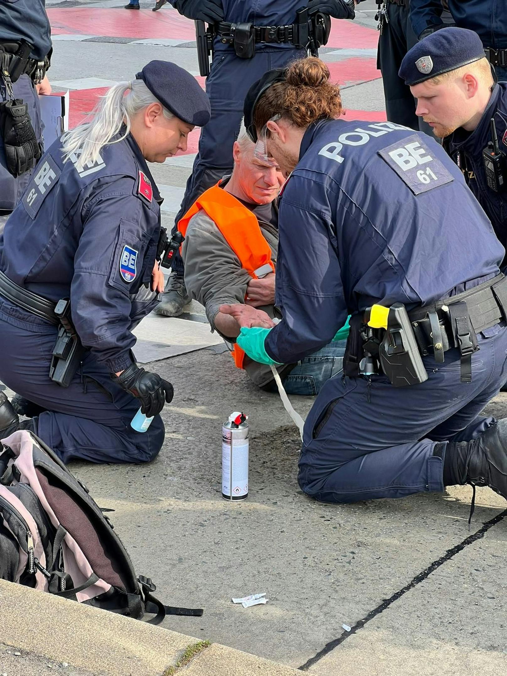 Die Polizeibeamten entfernen die Klima-Kleber von der Straße.