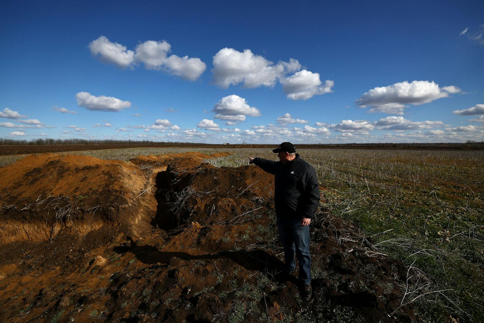 Getreidefarmer Oleksandr Klepach vor seinem von einem Schützengraben völlig zerfurchten Feld in Snihuriwka,&nbsp;Oblast Mykolajiw, im Februar 2023.