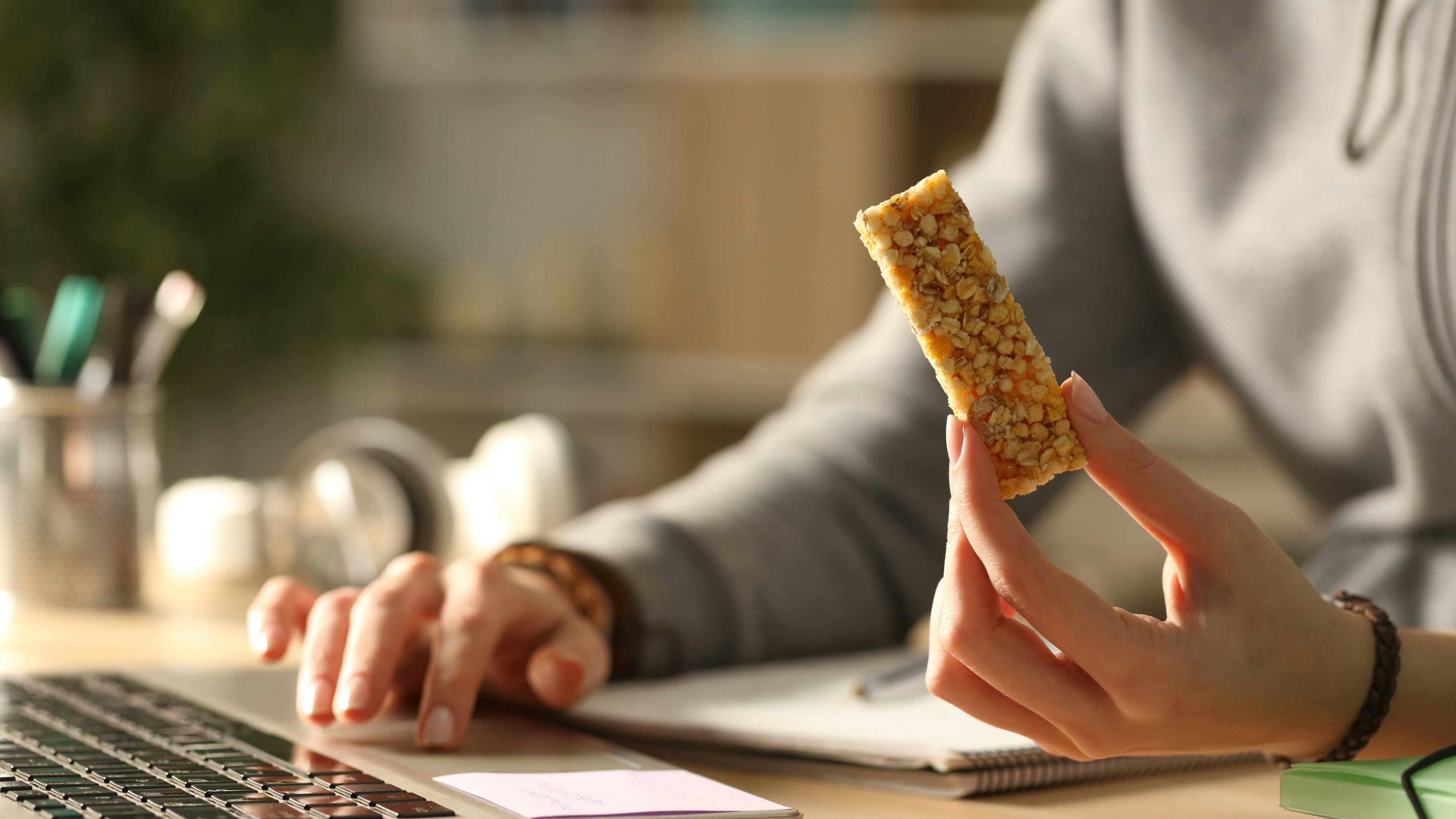 Student hands holding snack bar at night e-learning