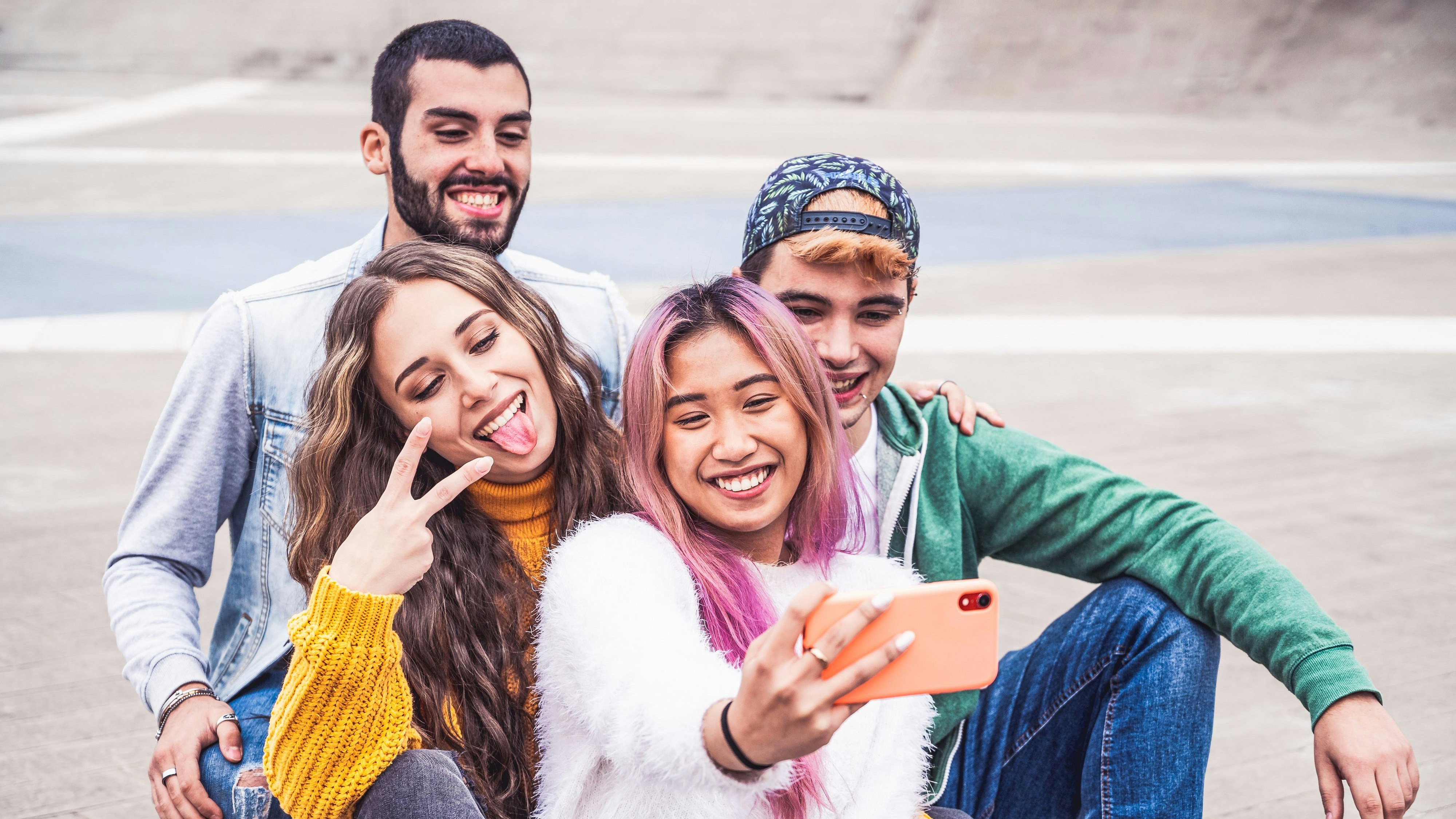 Happy multiracial teenage friends smile while taking a selfie in the city street - New normal lifestyle concept with young students having fun together near to the campus