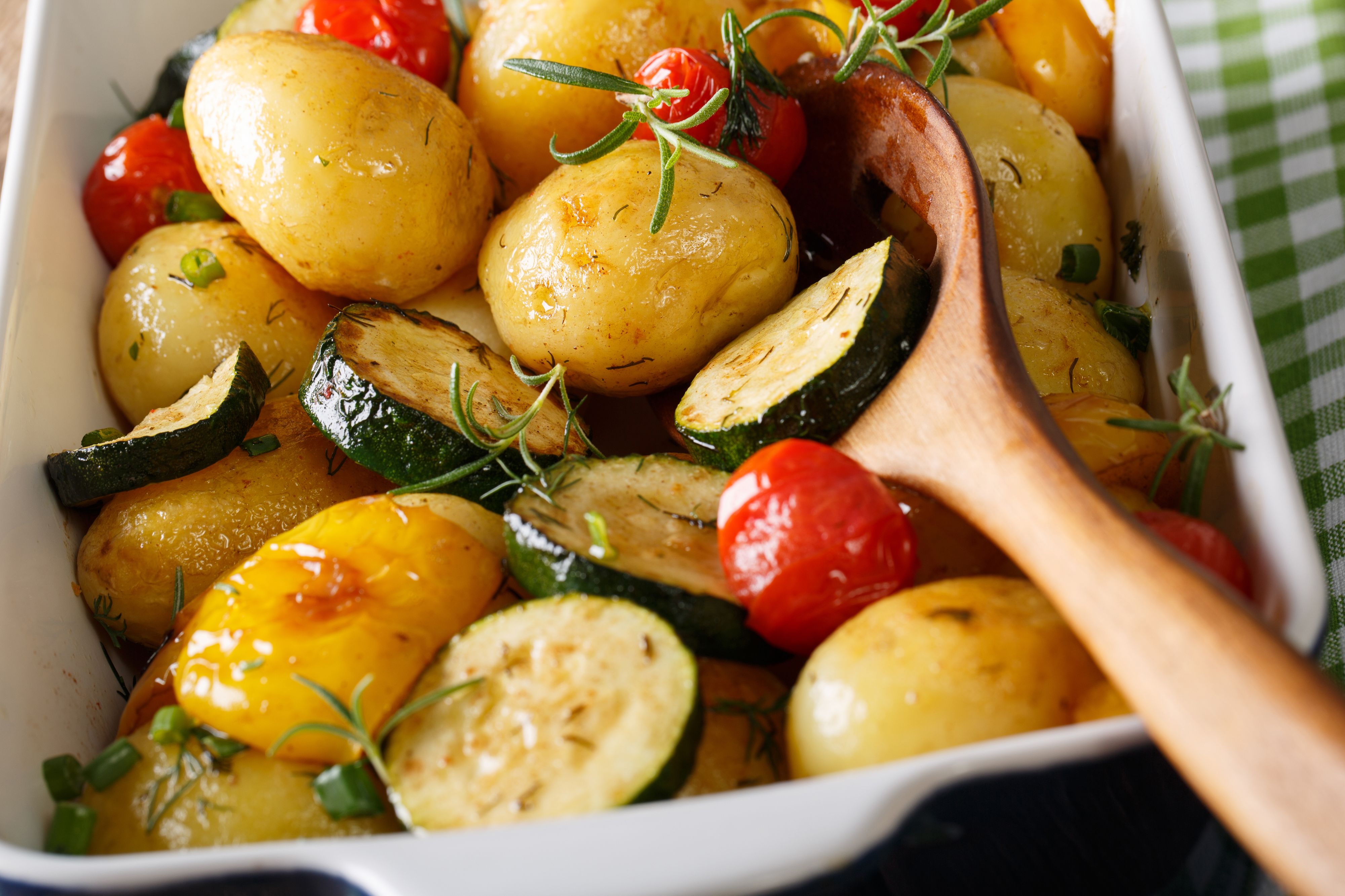 Tasty Food: whole potatoes baked with zucchini, bell pepper and tomatoes close-up in a baking dish. horizontal
