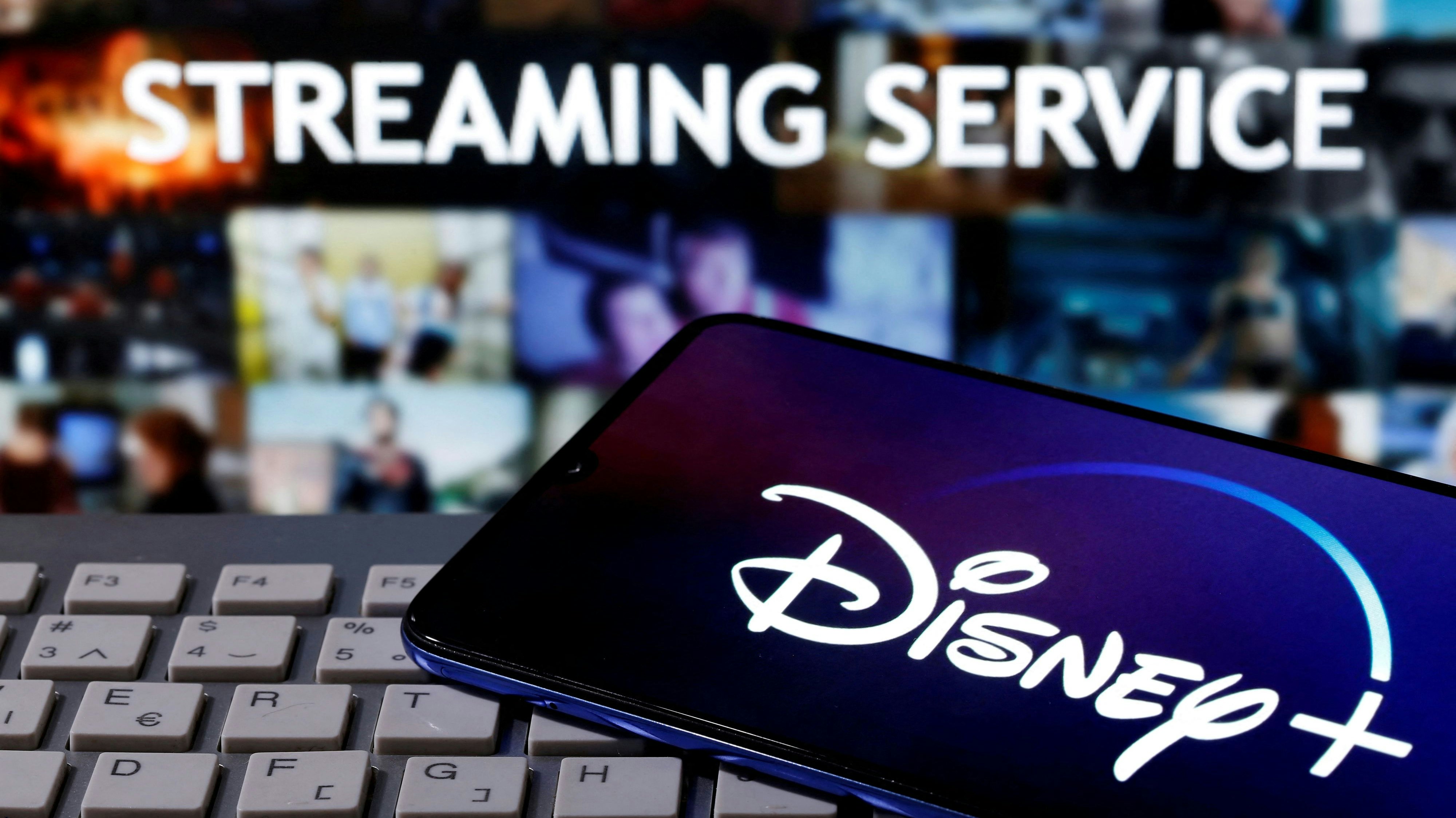 A smartphone with displayed "Disney" logo is seen on the keyboard in front of displayed "Streaming service" words in this illustration taken March 24, 2020. REUTERS/Dado Ruvic/File Photo