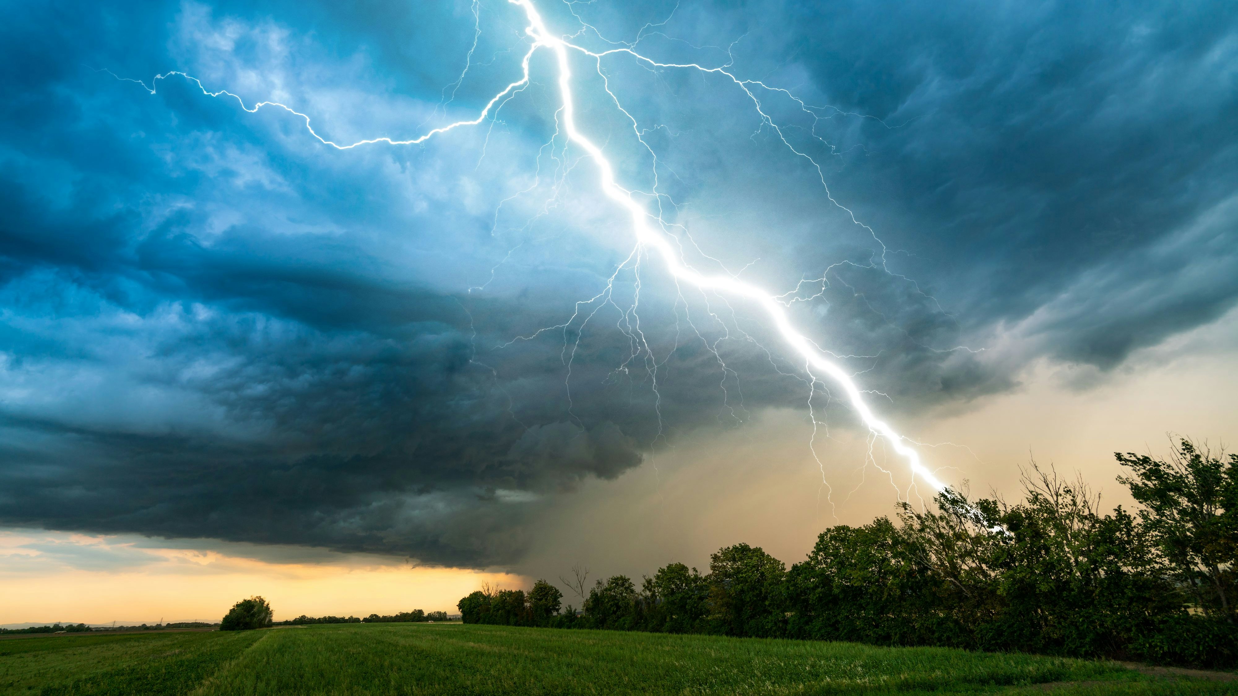 dramatic lightning thundertbolt bolt strike in daylight rural surrounding bad weather dark sky