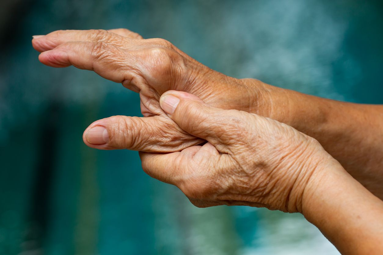 Trigger Finger, Senior woman's left hand massaging her thumb finger, Suffering from pain, Close up & macro shot, Swimming pool background, Office syndrome, Healthcare and massage asian body concept