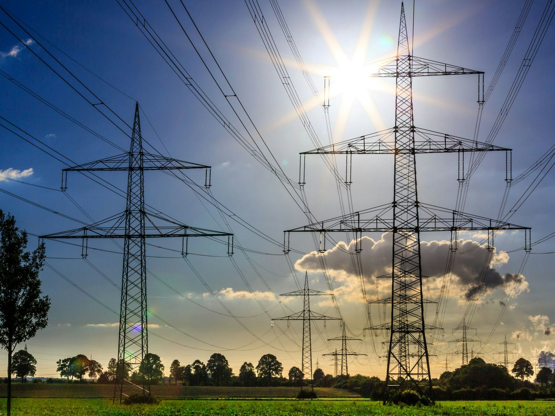 power lines on a green field in the sunset