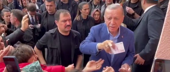 Erdogan verteilt vor einem Wahllokal Geldscheine. 