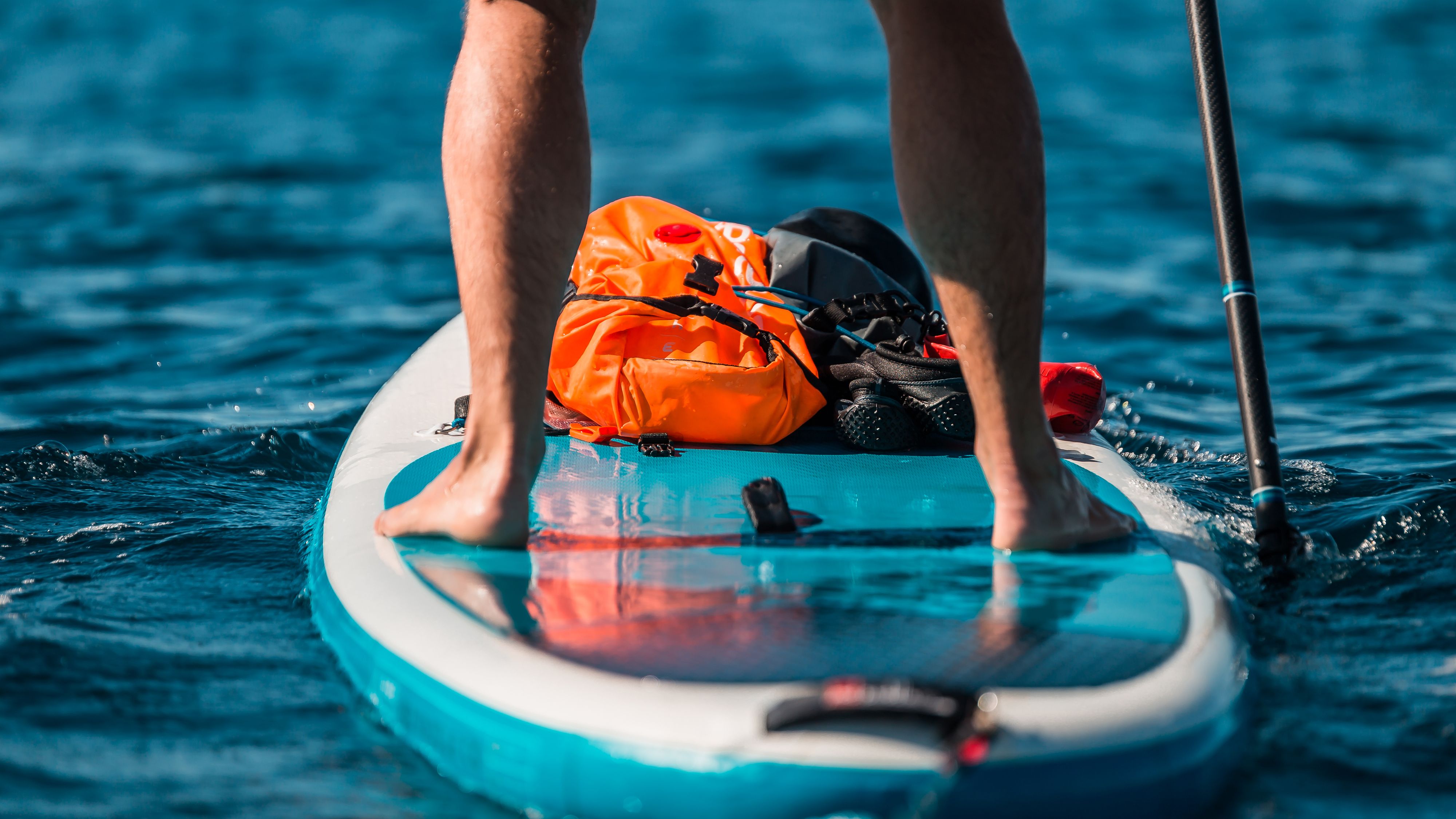 Young athletic man paddling on a SUP stand up paddle board in blue water sea in Montenegro