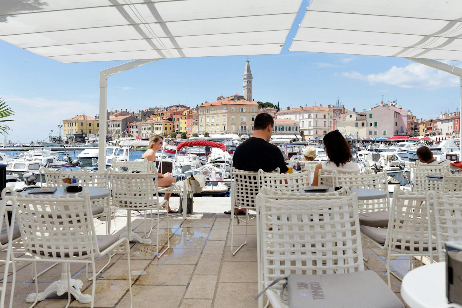 Gäste in einem Straßen-Café am Hafen von Rovinj mit Blick auf die Altstadt. Für die Top-Lage löhnt man in den meisten Lokalen extra.