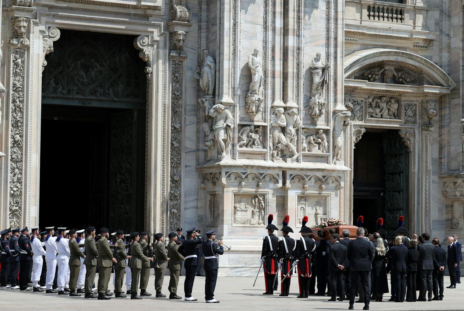 Angehörige des Militärs stehen in einer Ehrengarde, während Sargträger den Sarg in den Mailänder Dom tragen.