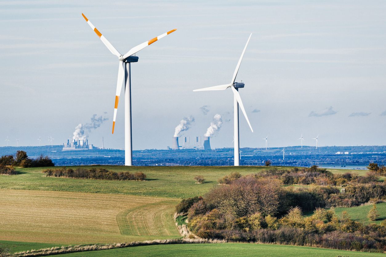 Mechernich in Deutschland. Zwei Windräder vor Braunkohlekraftwerken der RWE.