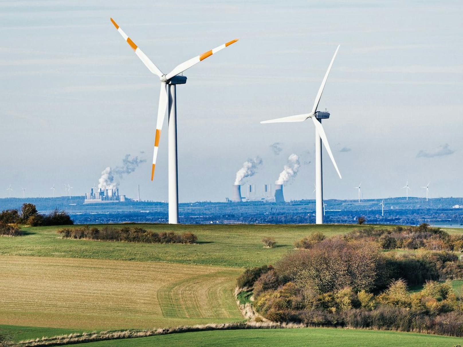 Mechernich in Deutschland. Zwei Windräder vor Braunkohlekraftwerken der RWE.