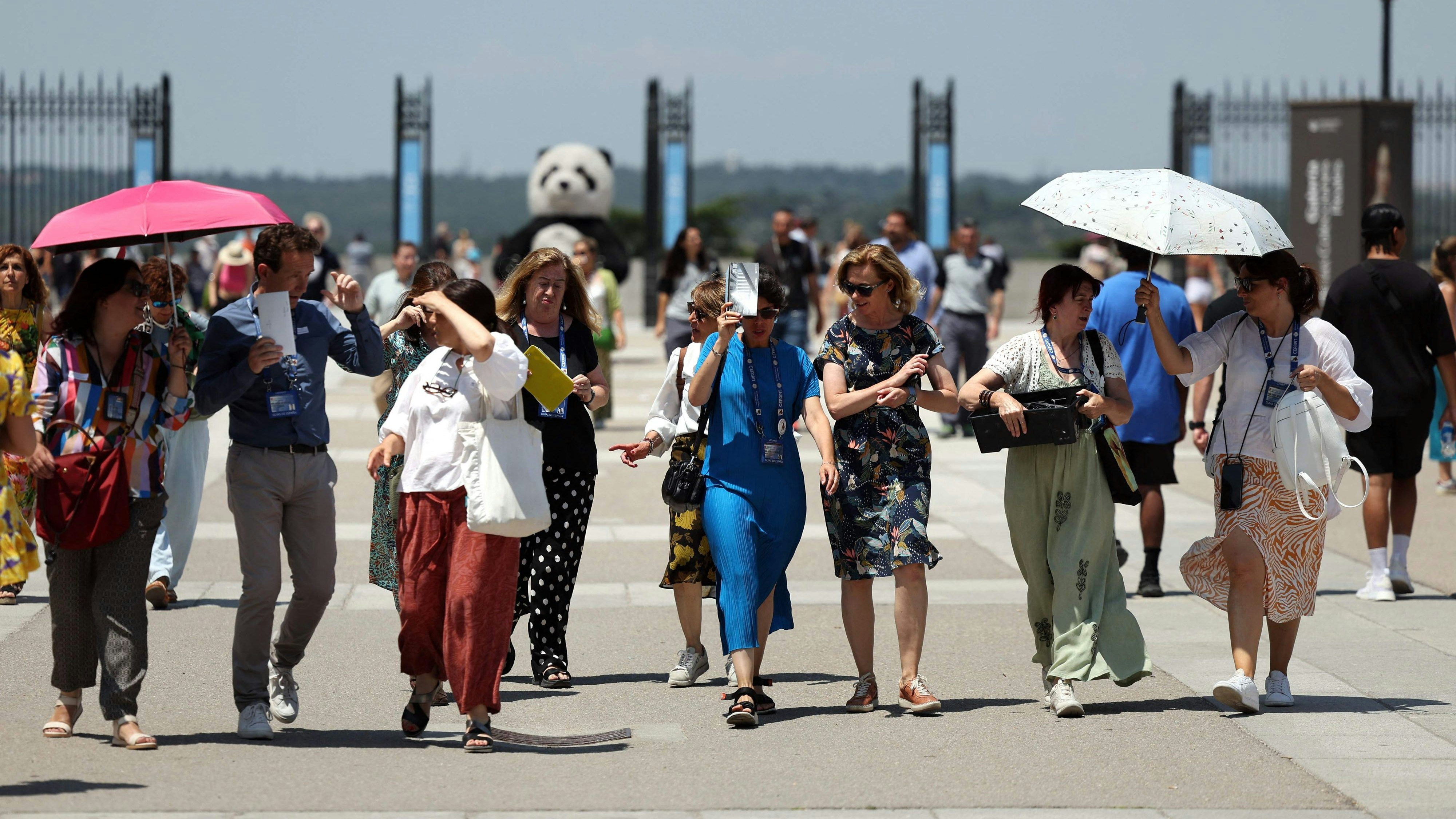 Touristen sind in Sevilla mit Sonnenschirmen unterwegs.